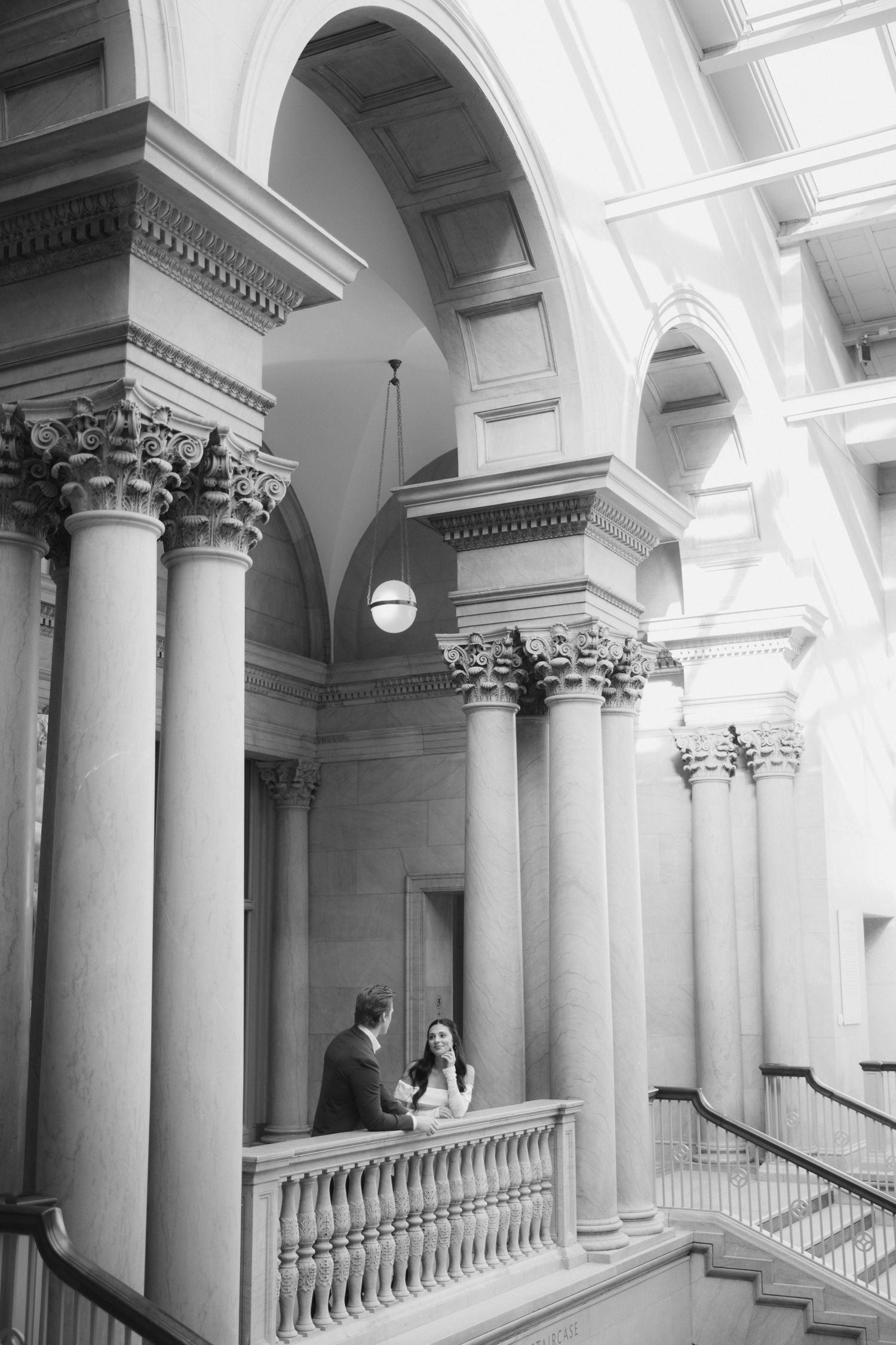 A black and white photo showing classical architecture with tall columns and arched ceilings.