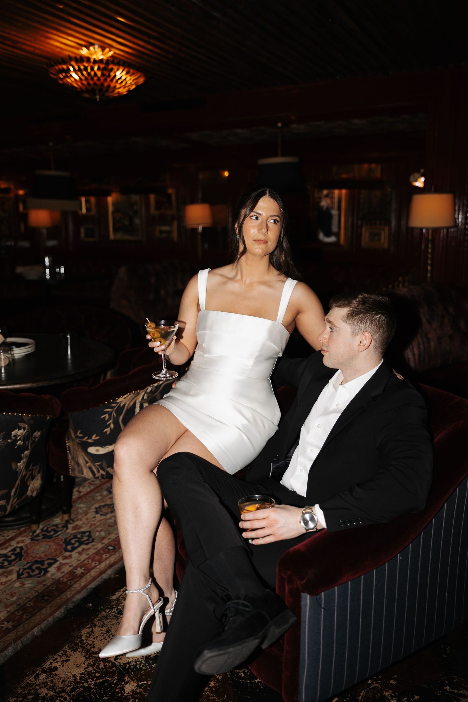 A romantic scene unfolds in a dark restaurant as a couple shares a close moment on a bench seat.