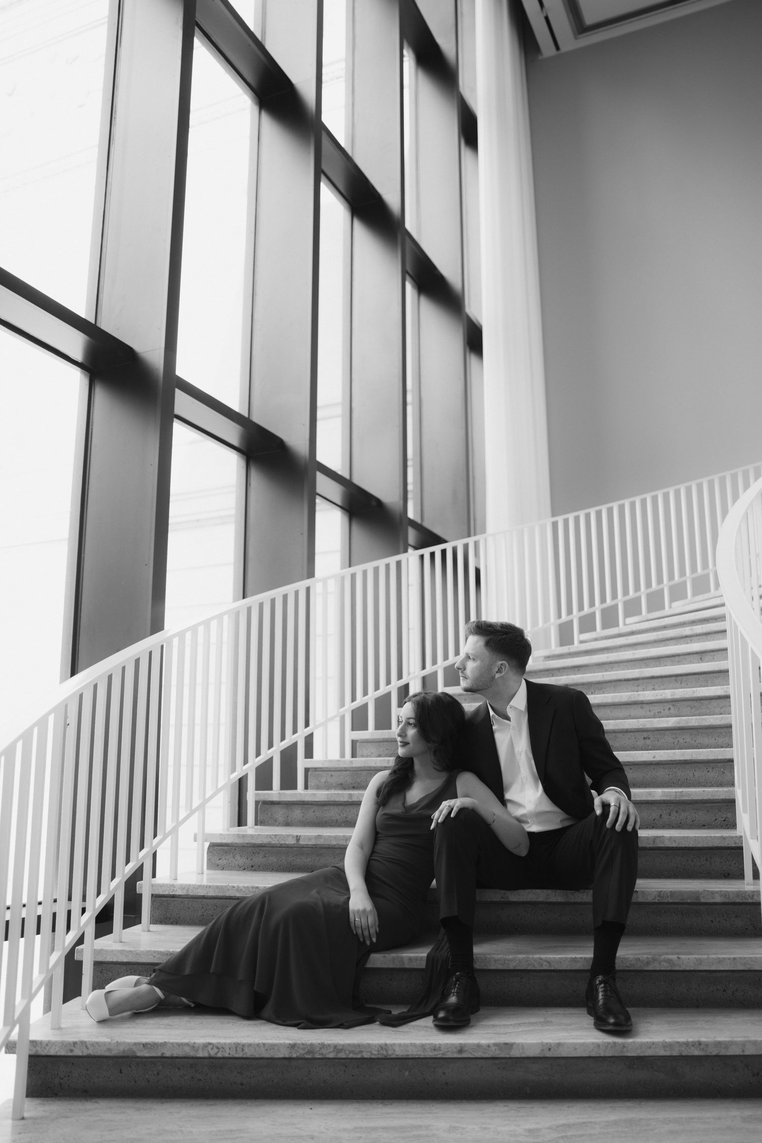 A romantic black and white photo series showing a couple lounging on modern architectural steps.