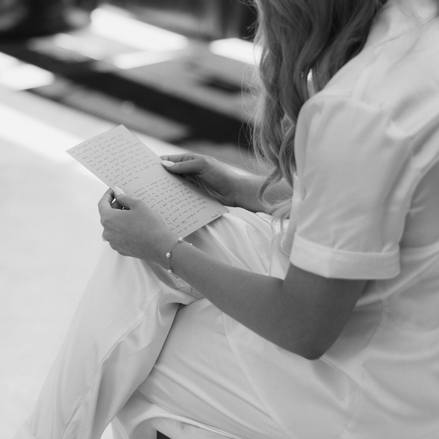 Medical professional in white uniform takes notes while sitting at desk in black and white photograph.