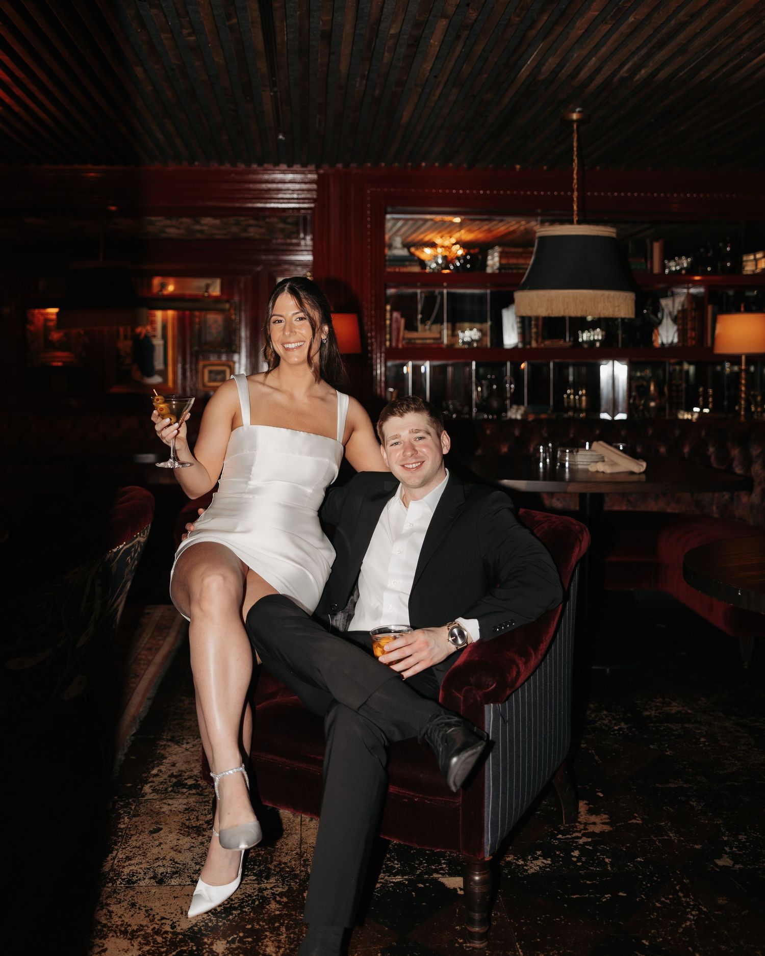 A couple in formal attire share an intimate moment in a dimly lit restaurant booth.