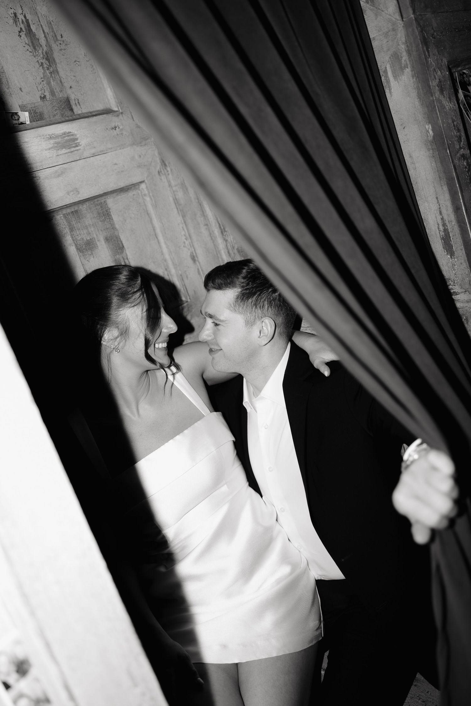A series of black and white photos showing figures in formal attire behind dark curtains.