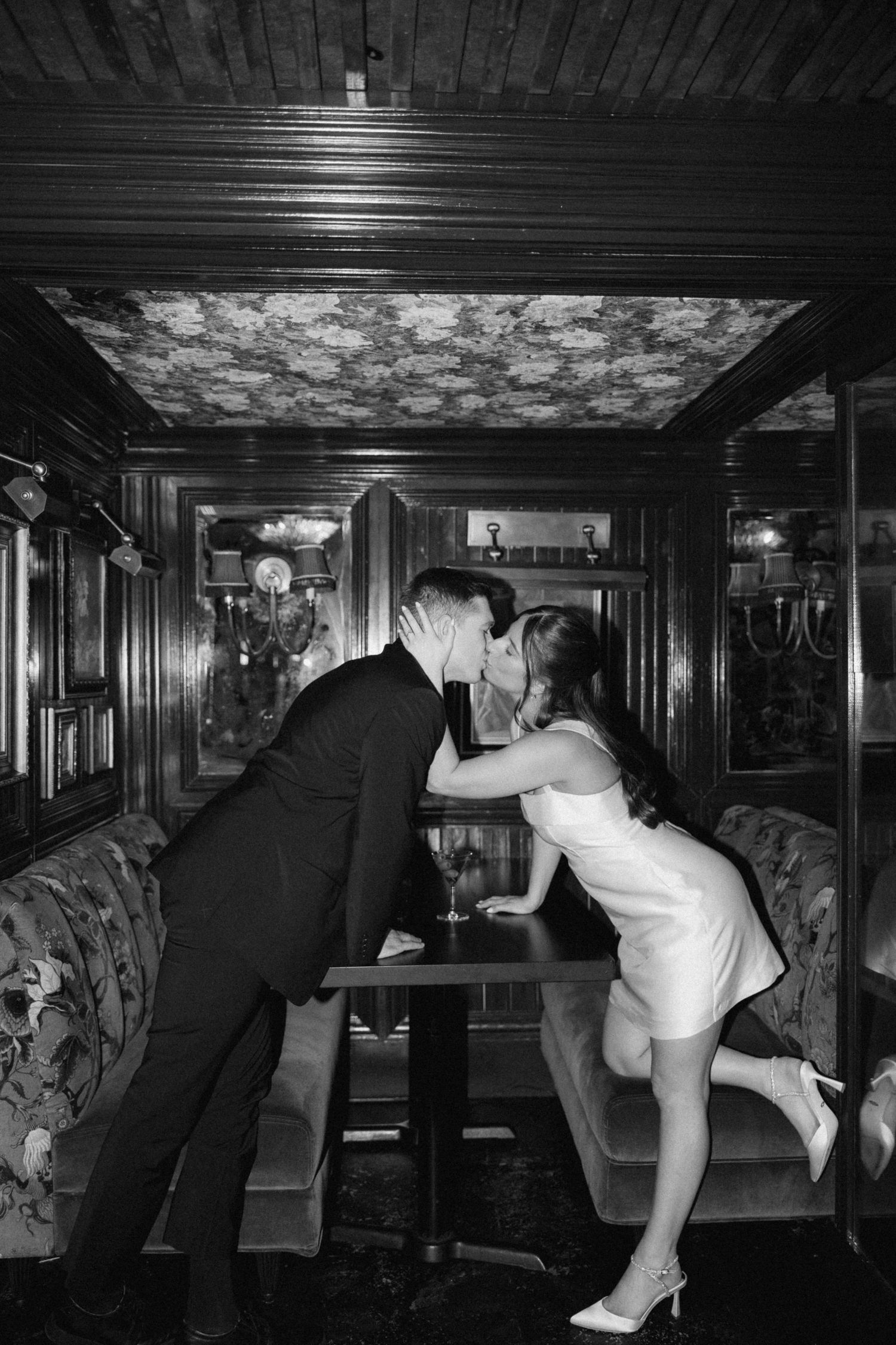 Black and white sequence showing a person in formal attire performing acrobatic moves in an elegant hallway.