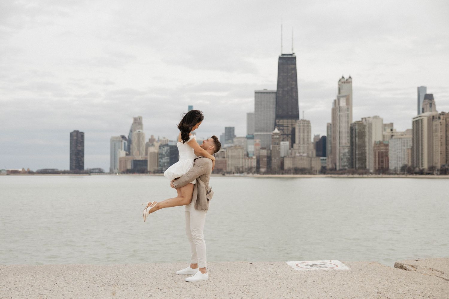 Couple sharing romantic lift pose on Chicago lakefront with iconic city skyline and John Hancock tower.