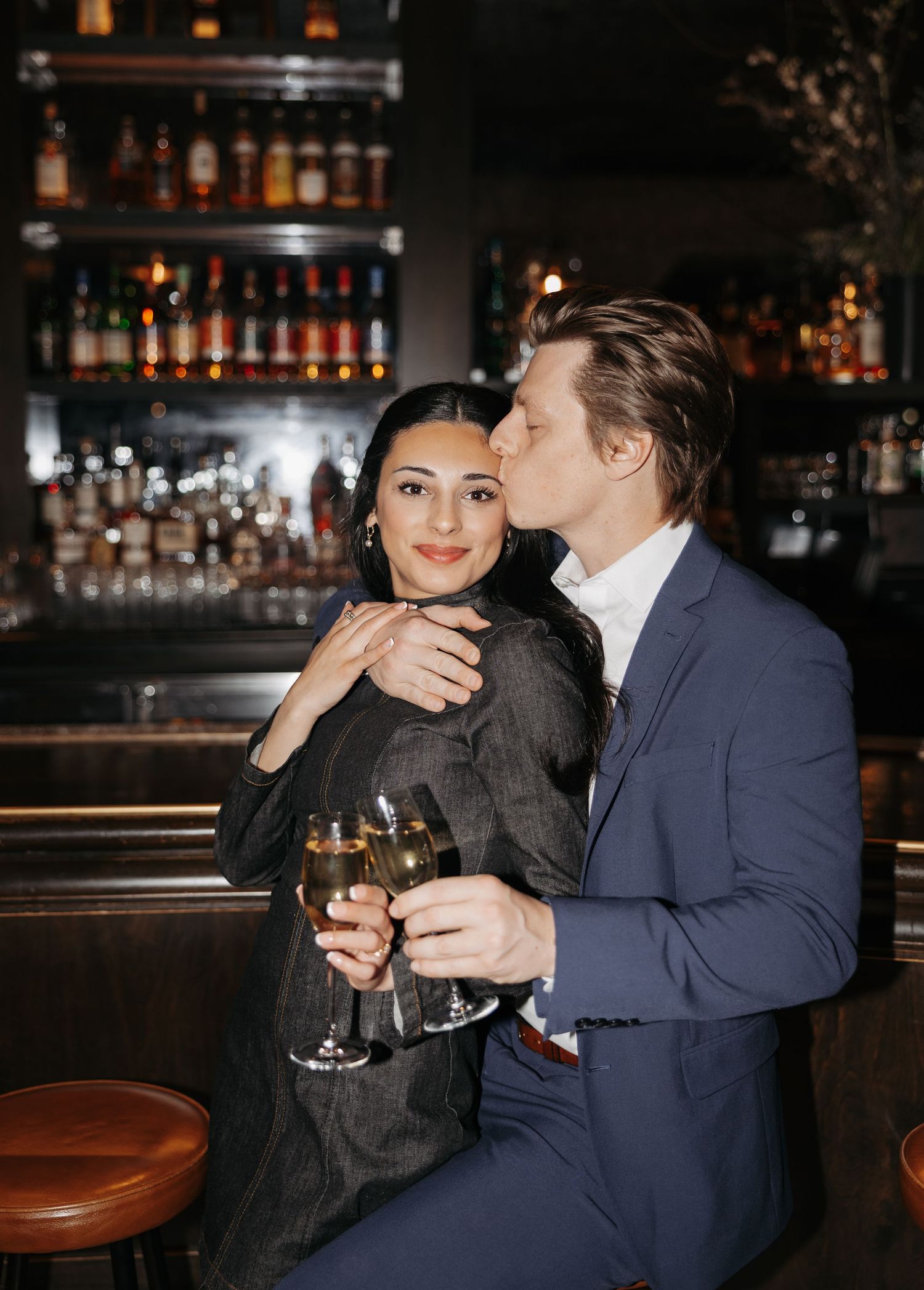 Couple sharing drinks and intimate moments at a dimly lit bar counter.