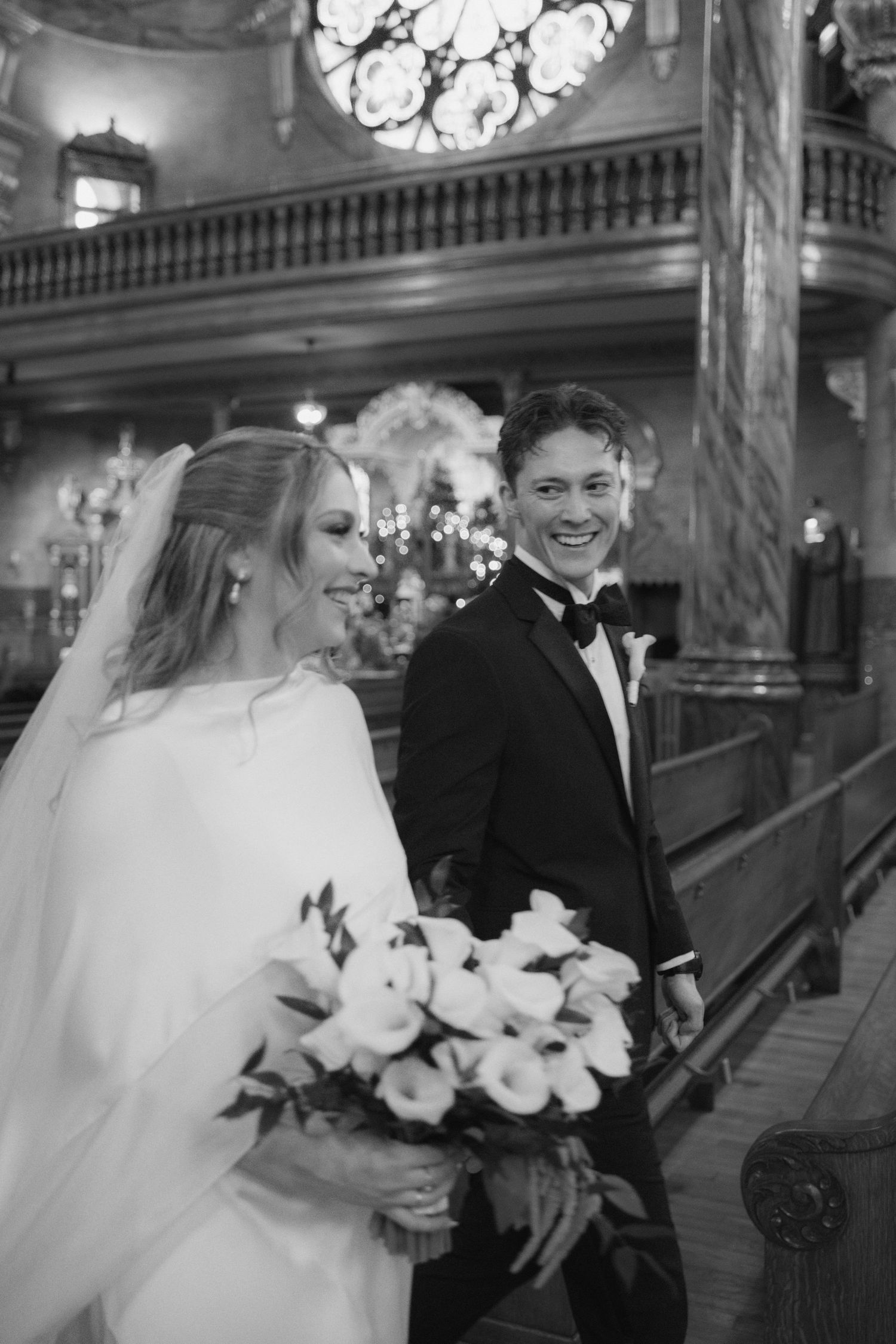 A bride and groom share joyful moments together in an elegant indoor venue with ornate architectural details.