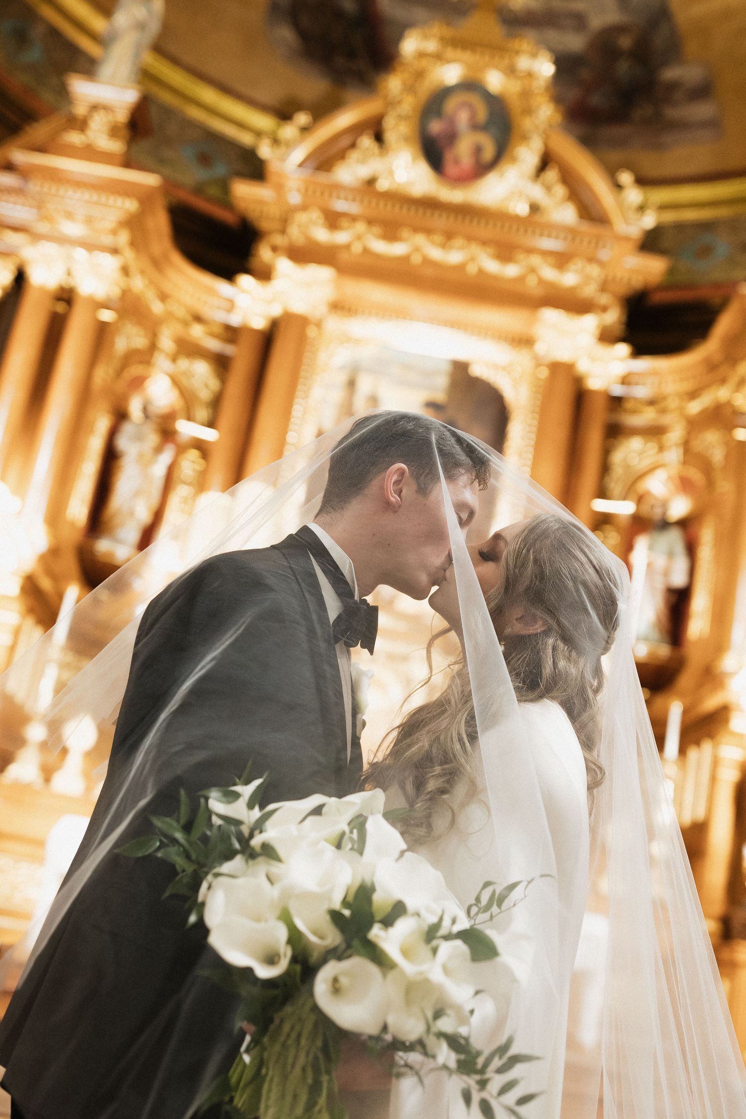 Elegant wedding ceremony in an ornate church with golden decor and chandeliers.