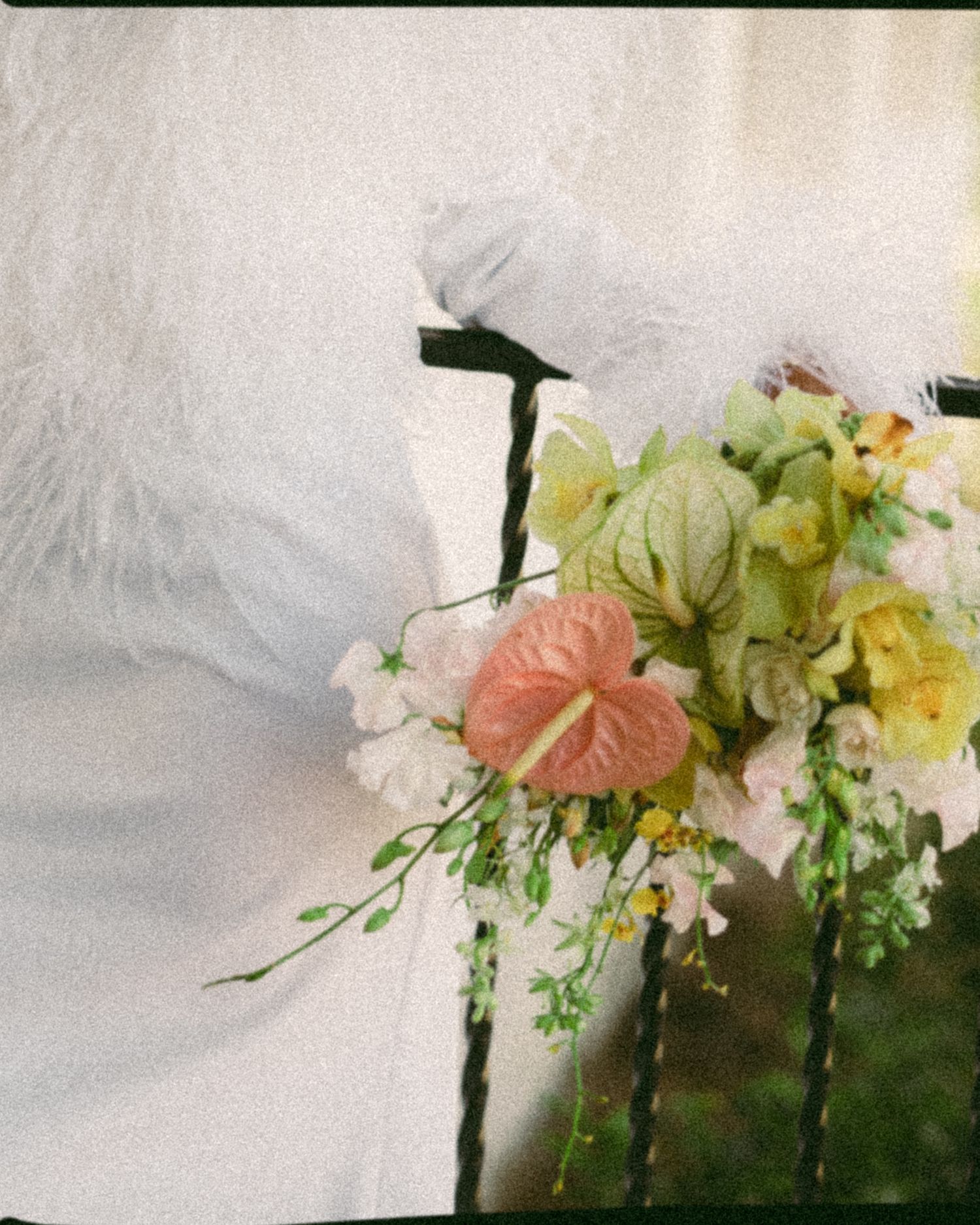 A delicate floral arrangement featuring pink anthurium and white flowers against a light background.