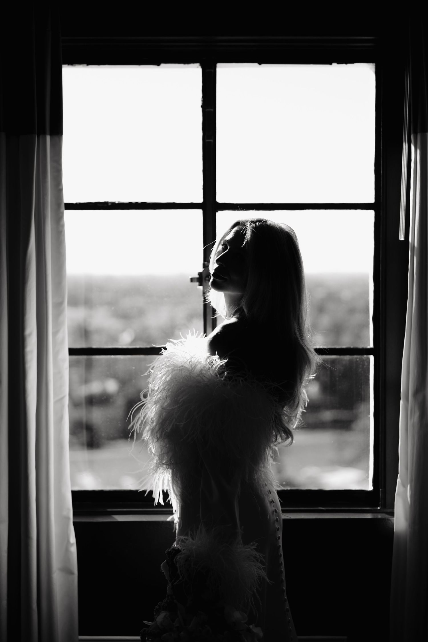 A series of black and white silhouettes by windows create a moody, cinematic composition with natural backlighting.