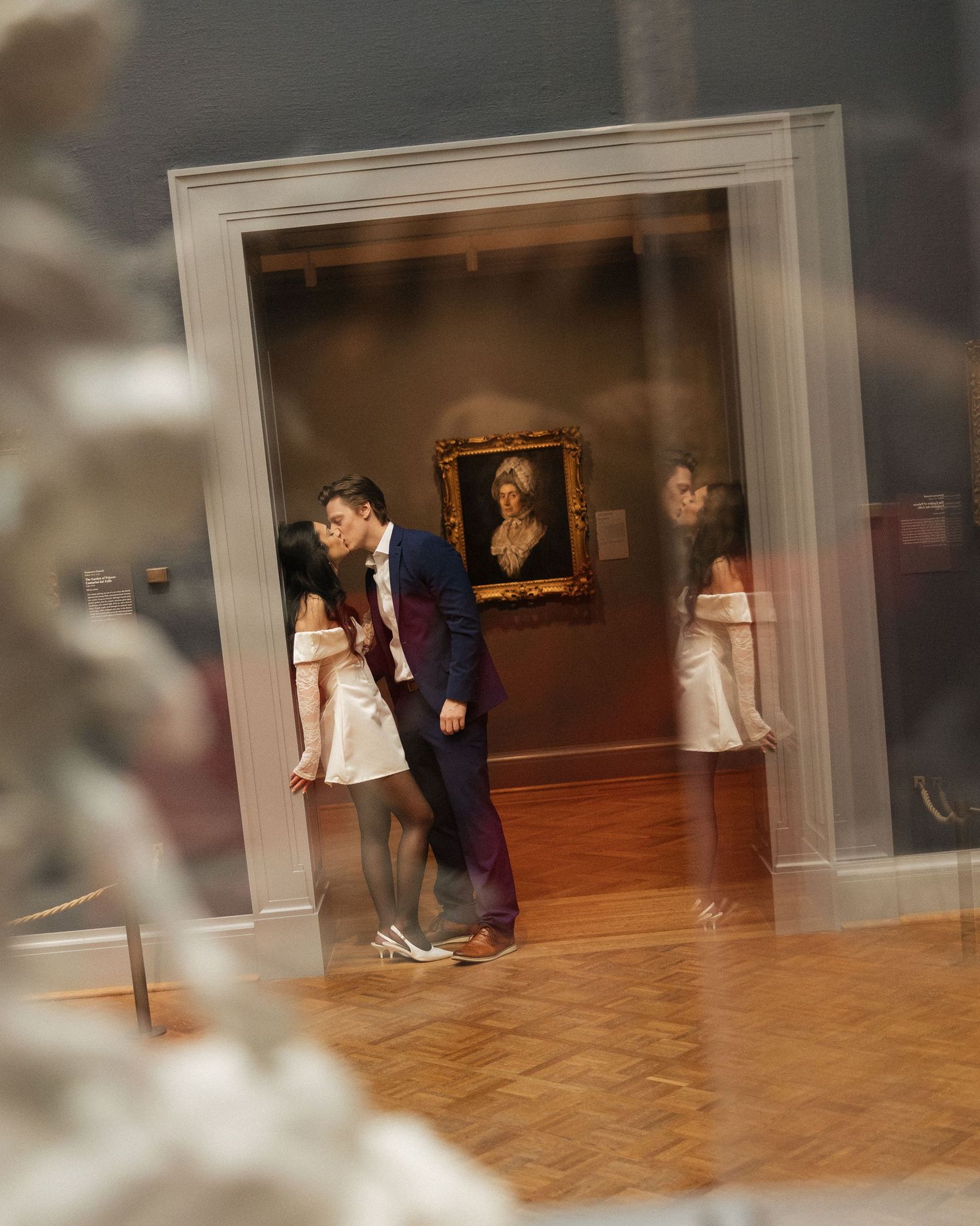 Blurred motion sequence of people moving through a wooden floored gallery space.
