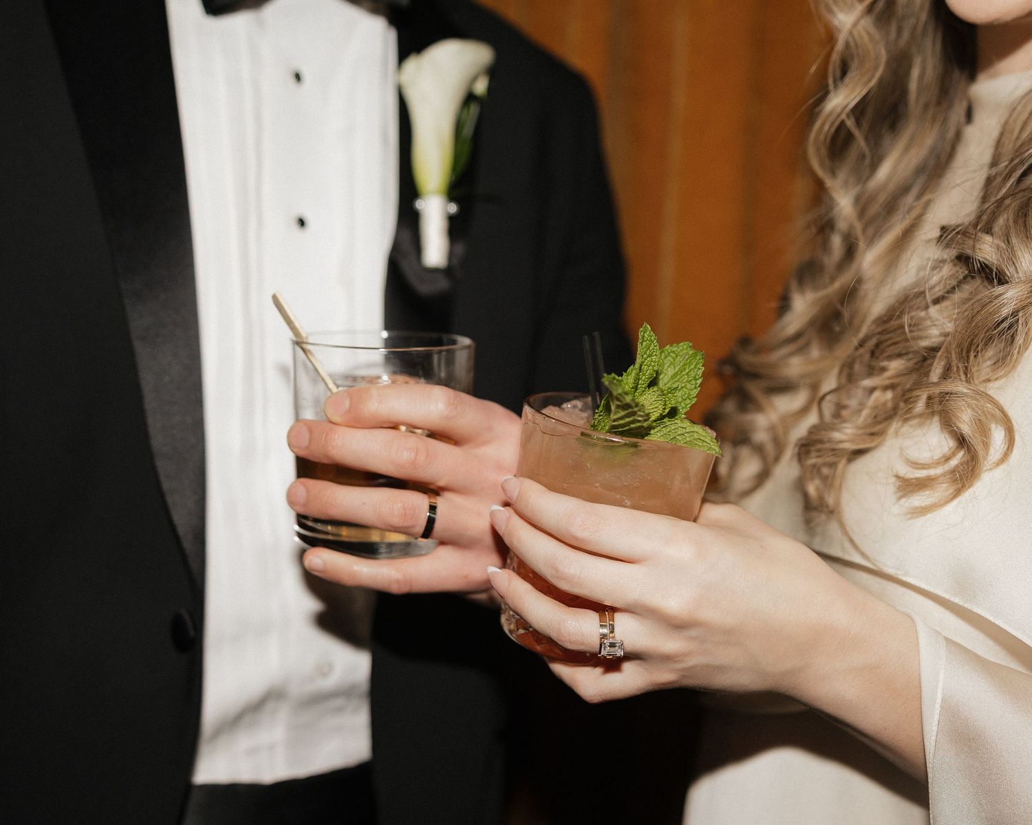 Close-up of hands holding cocktail glasses during a wedding celebration.