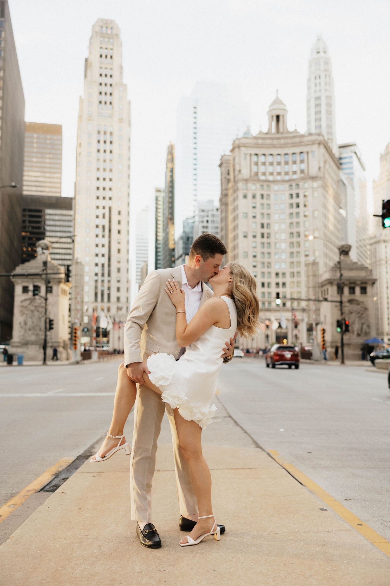 Couple sharing a romantic kiss on Michigan Avenue in Chicago, with iconic skyscrapers in the background.