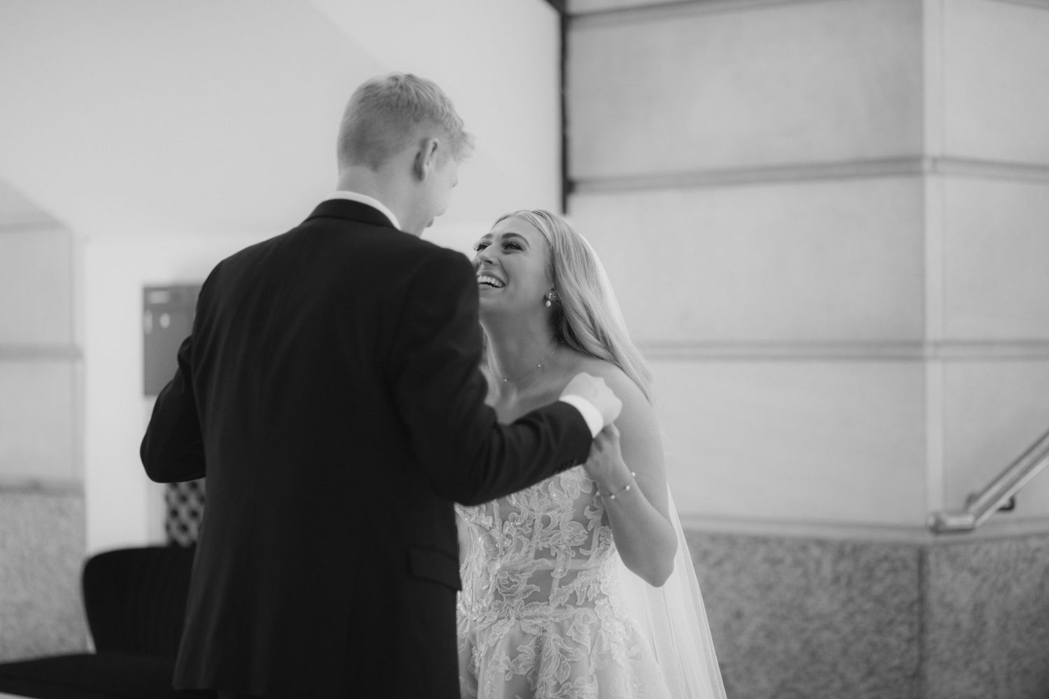 Black and white wedding photos show intimate moments between newlyweds in a classic architectural setting.