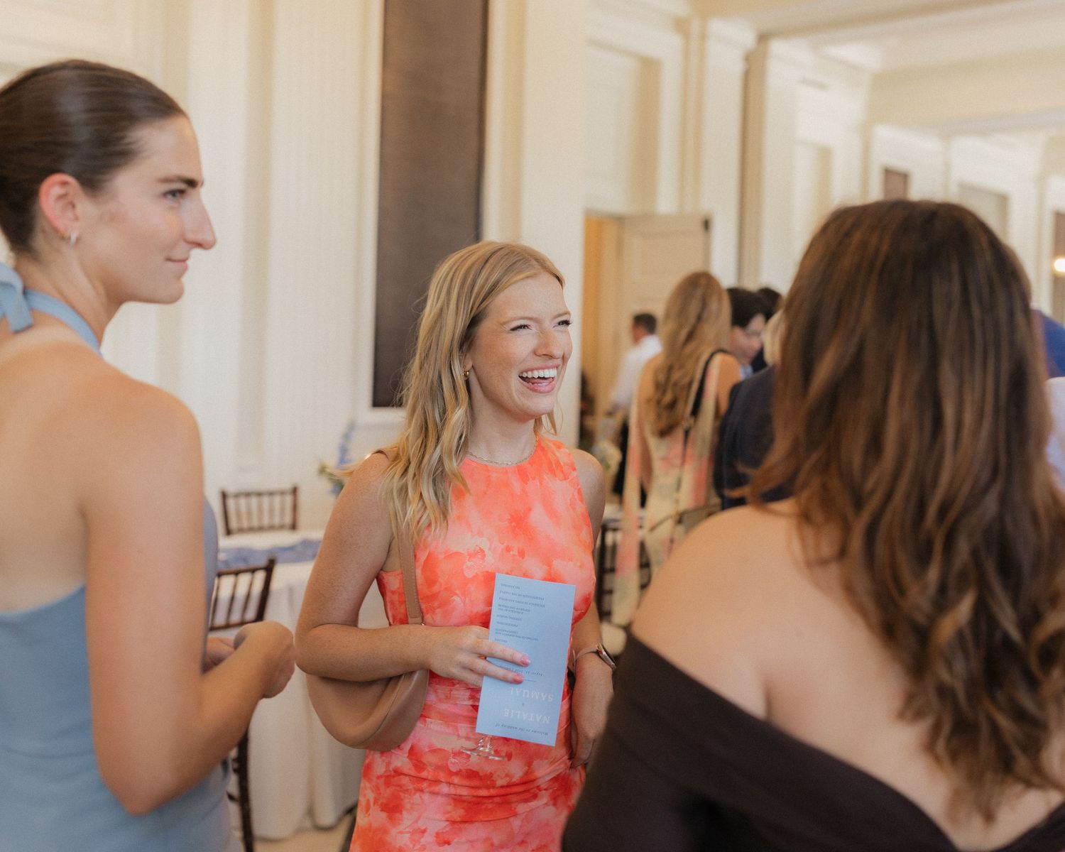 Wedding guests mingling and socializing in an elegant indoor venue with bright decor and formal attire.