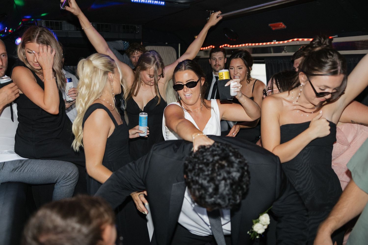 Party crowd dancing and celebrating in a limo or party bus at night.