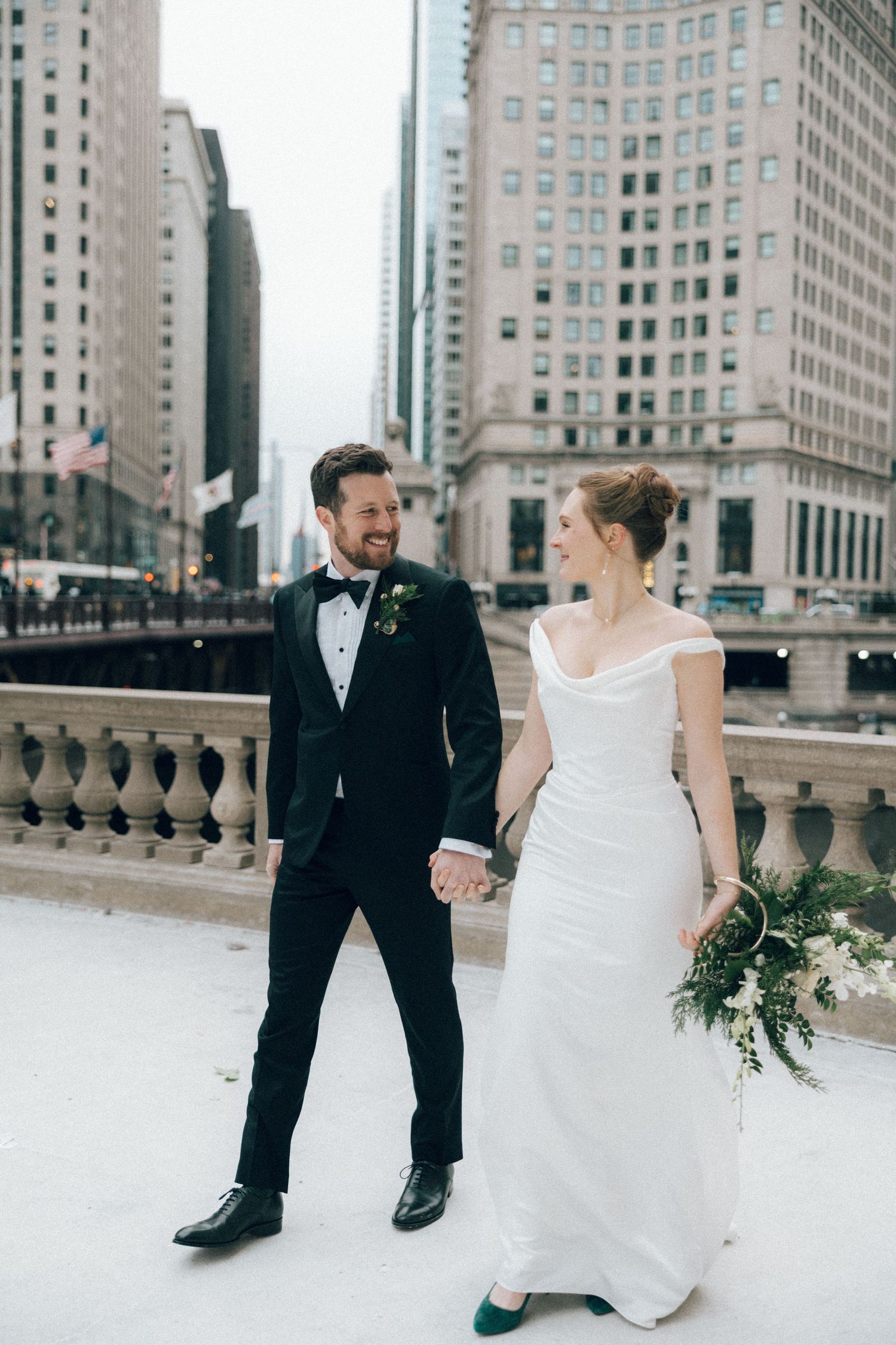 A bride and groom share joyful moments during their winter wedding photoshoot on a snowy urban terrace.