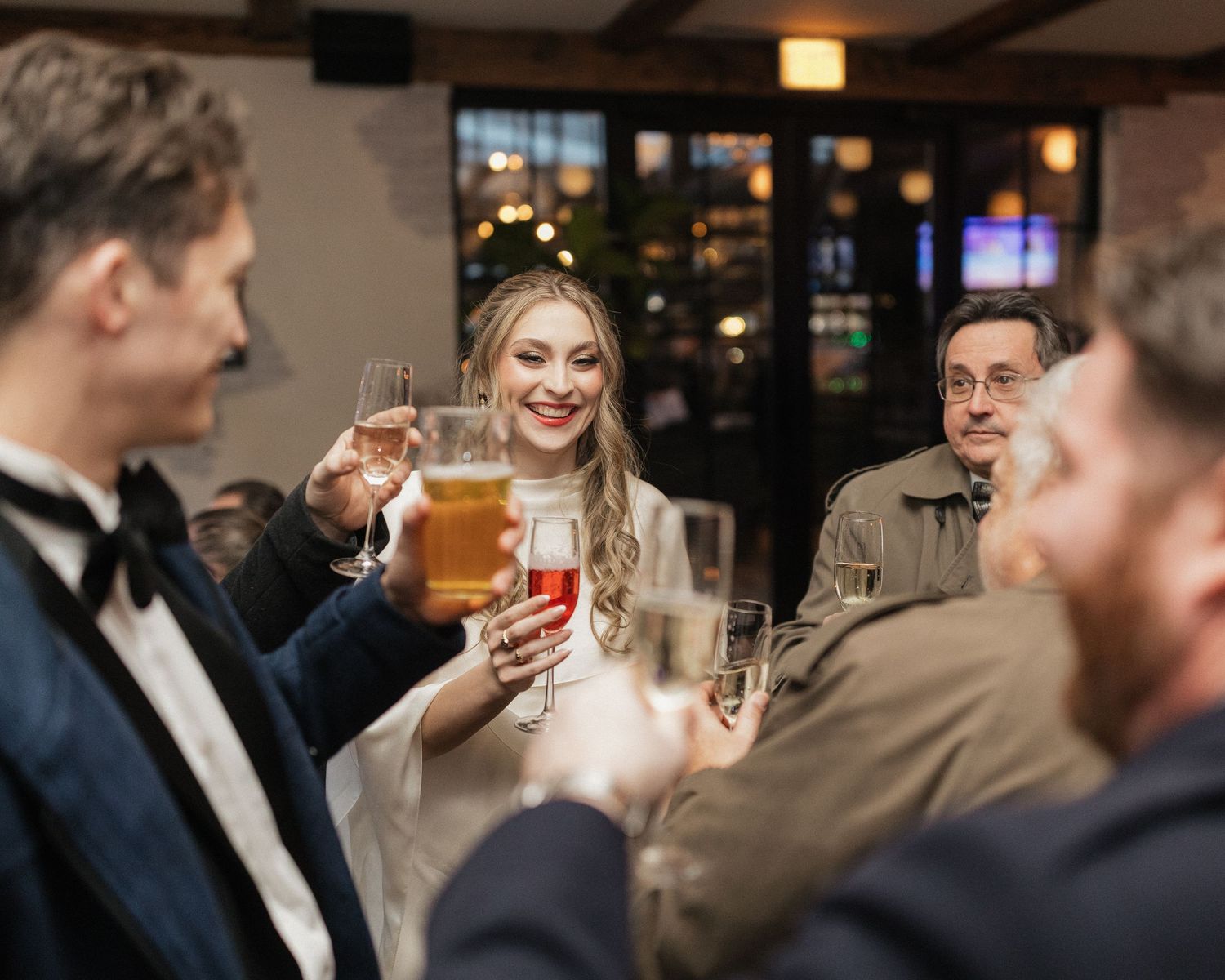 Wedding reception guests raising glasses in celebration at an evening party.