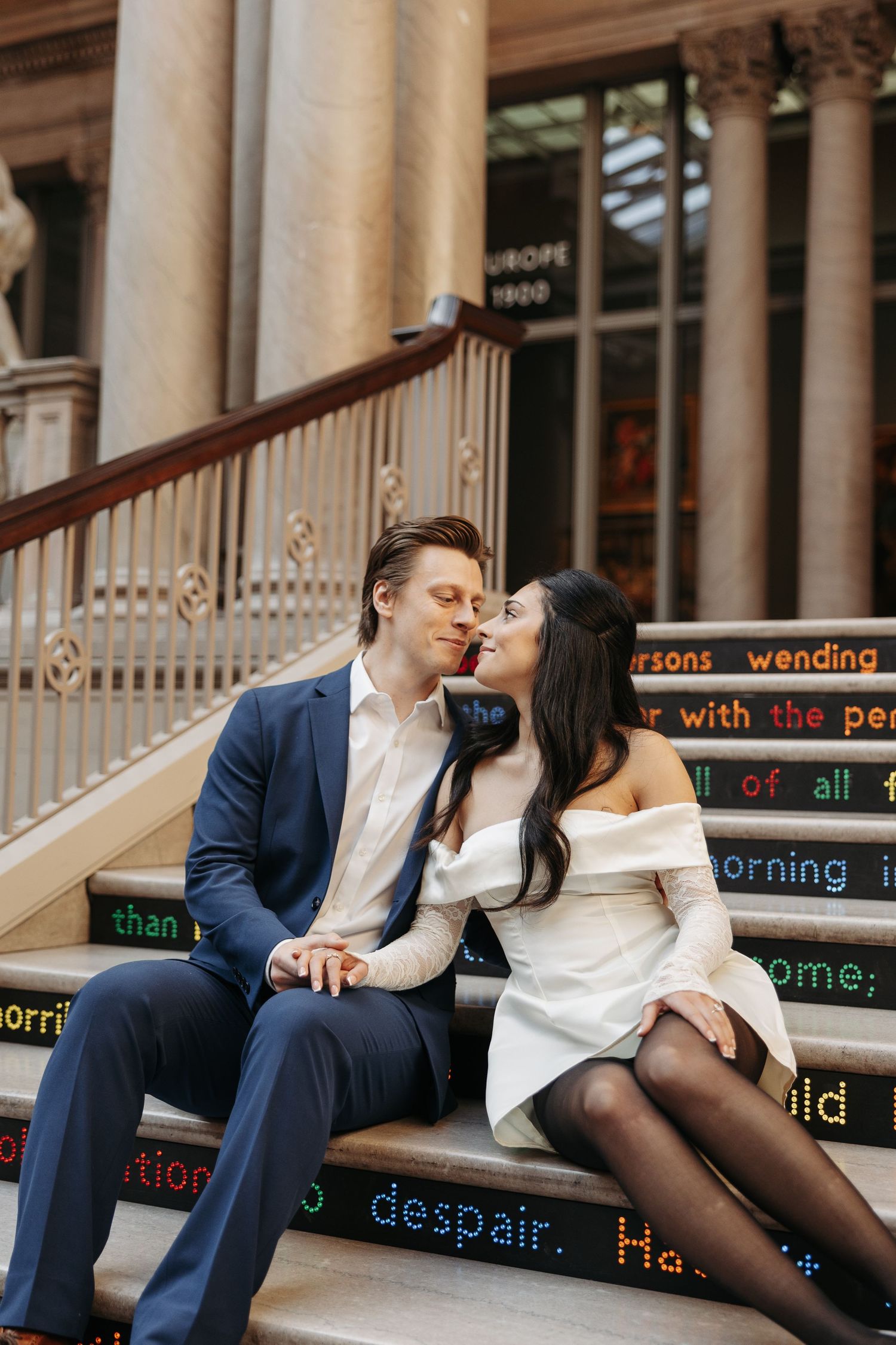 A couple shares an intimate moment on decorative steps with text inscriptions.
