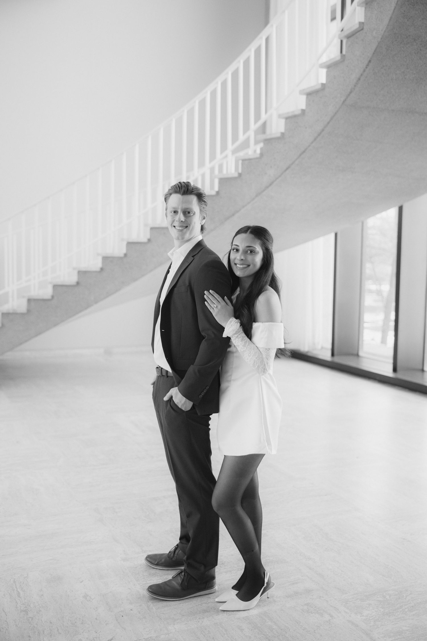 Black and white photo series showing a couple dancing playfully near white stairs.