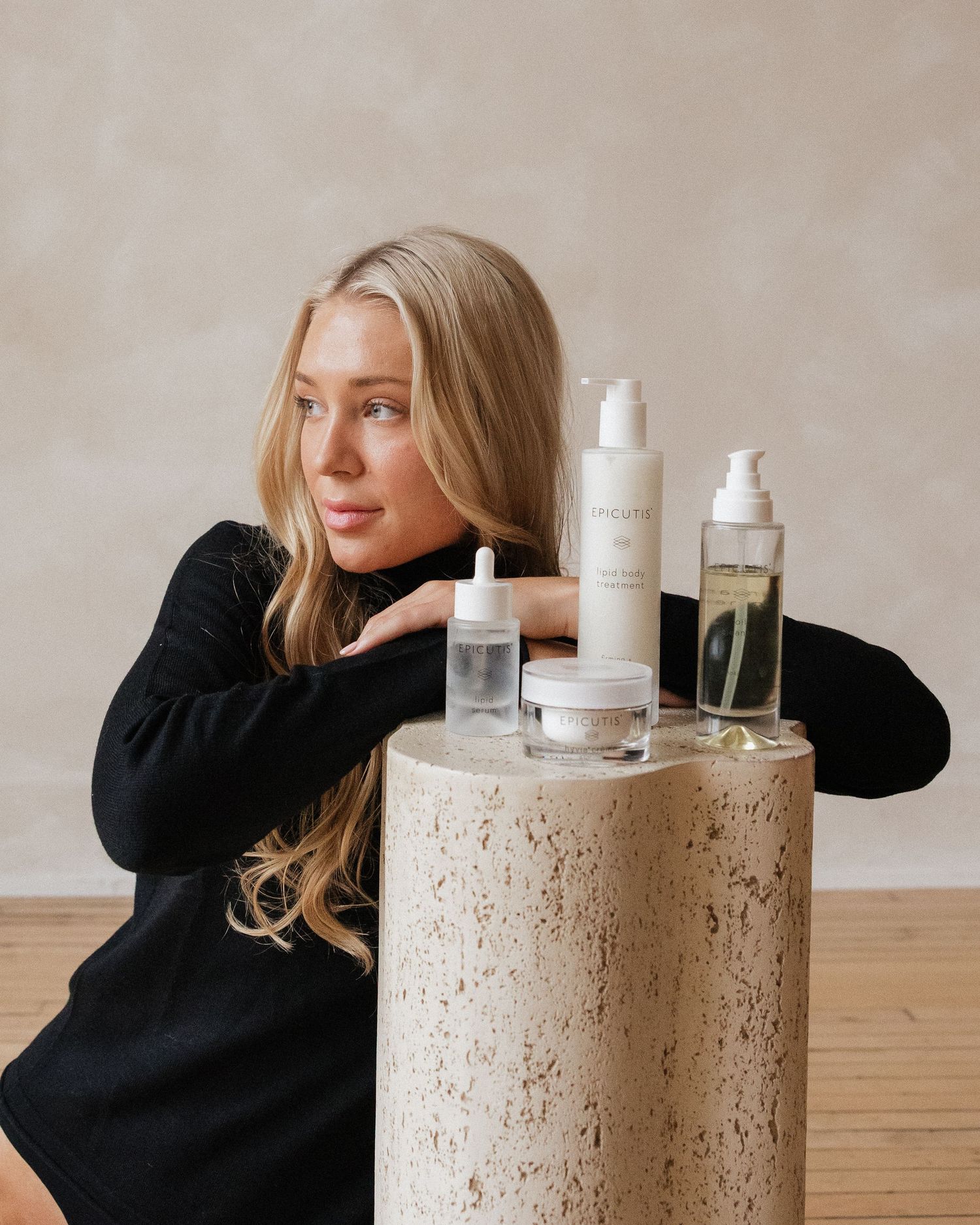 Beauty product display with white bottles arranged on textured concrete pedestal in warm studio lighting.