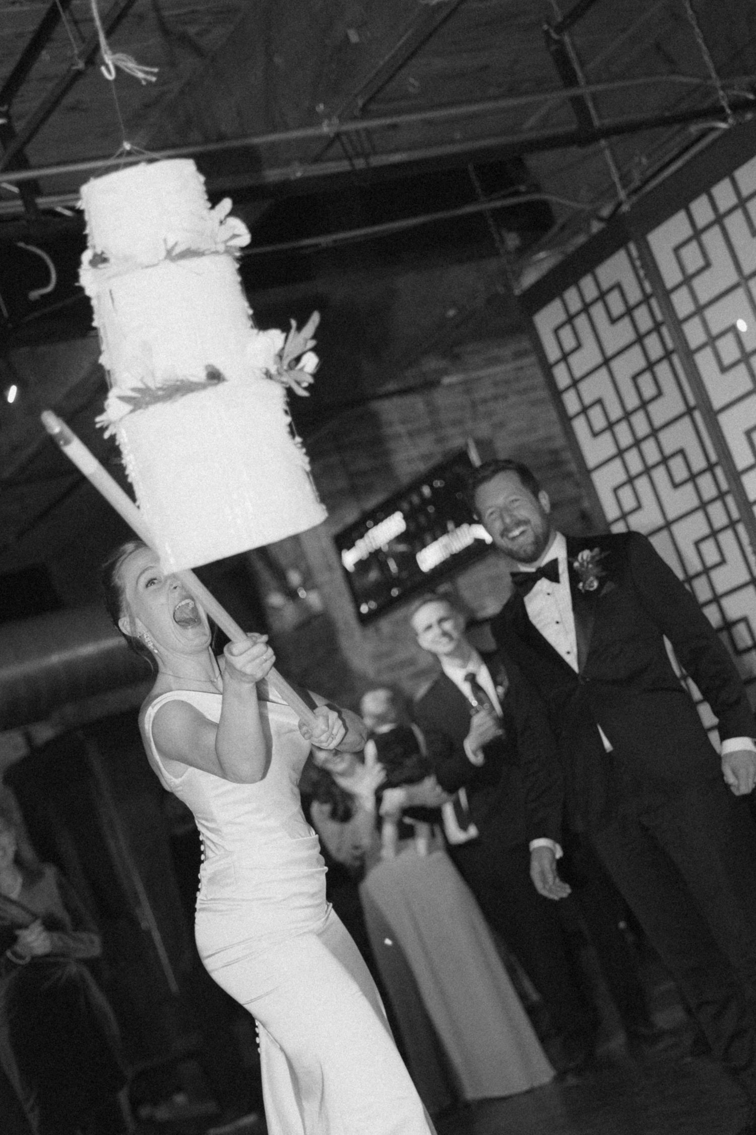 A sequence of black and white photos showing a bride carrying a wedding cake through a reception venue.