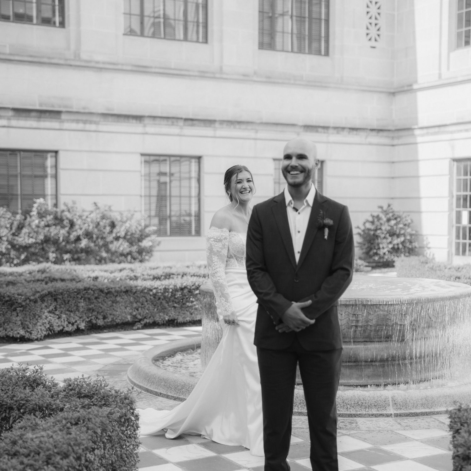 Elegant wedding couple poses outside a grand white building.