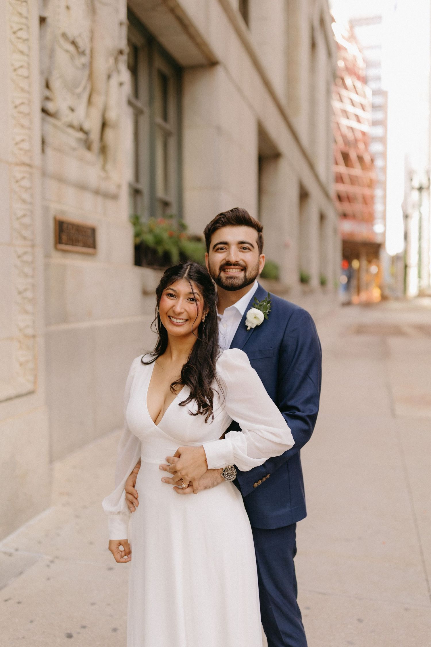 A joyful couple shares candid moments in three romantic portraits against a light stone building exterior.