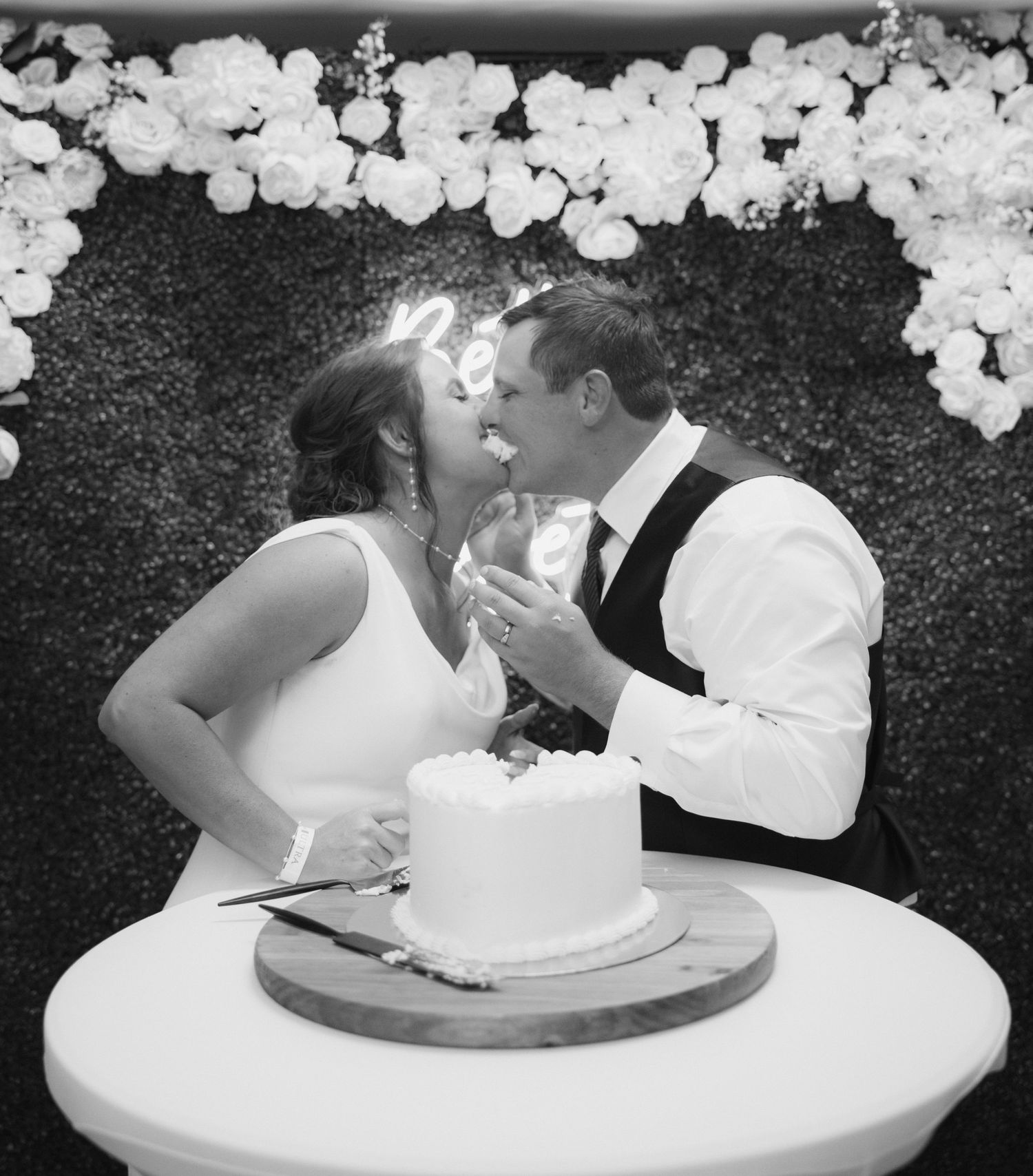Black and white sequence of newlyweds feeding each other wedding cake with white decorations.
