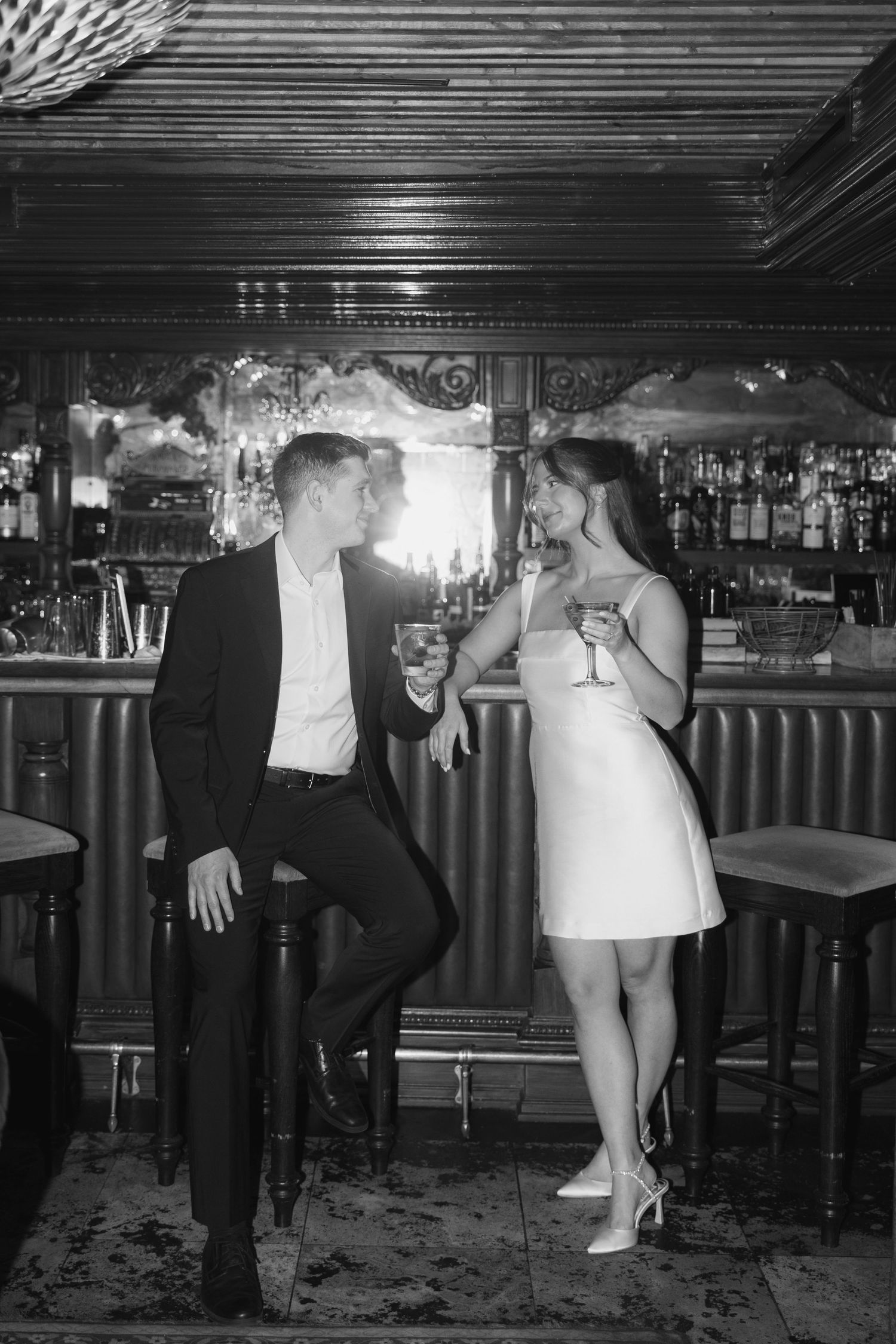Black and white photo series showing playful dance poses at a bar with people in formal attire.
