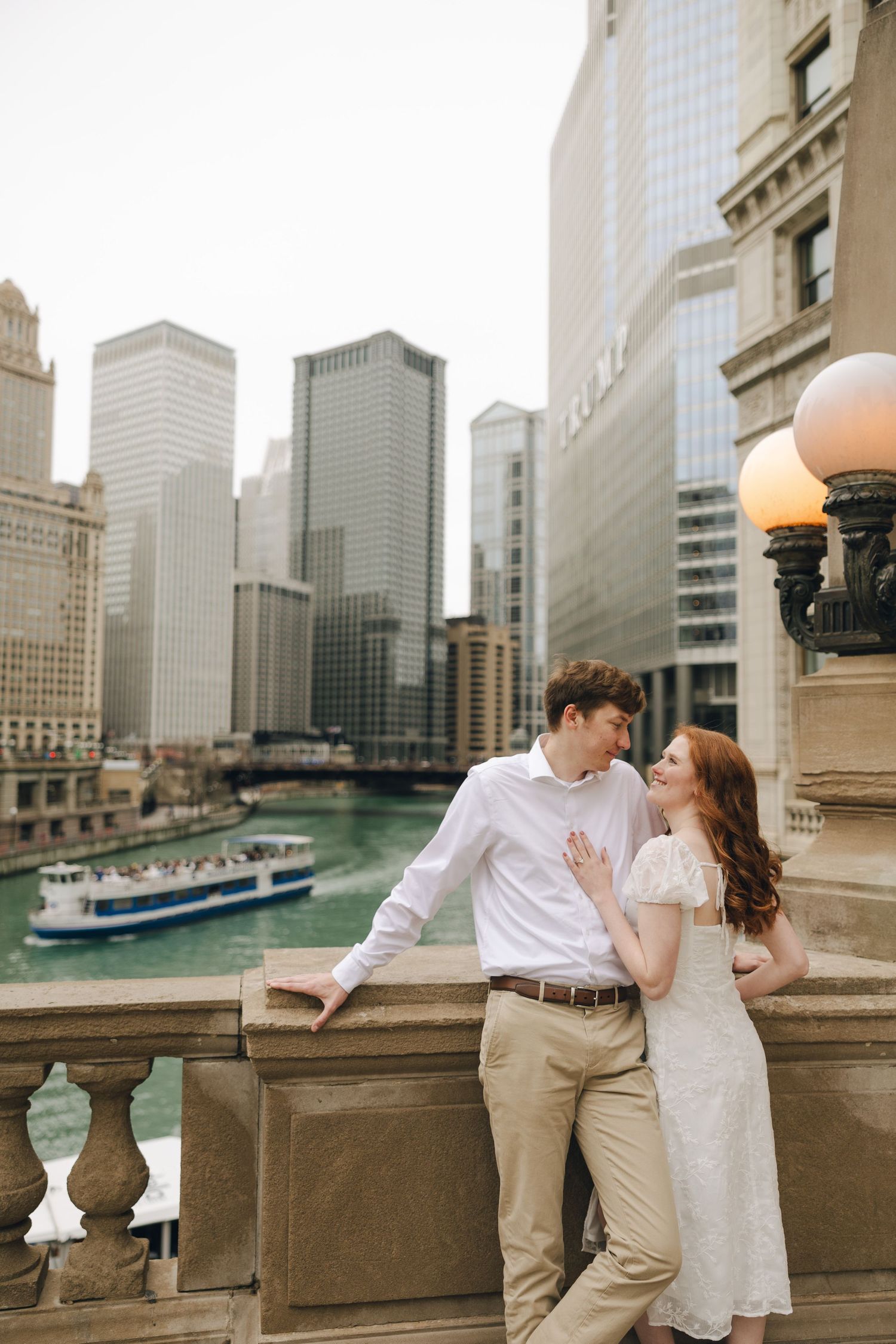 Couple sharing a romantic moment on a bridge overlooking the Chicago River with city skyline views.