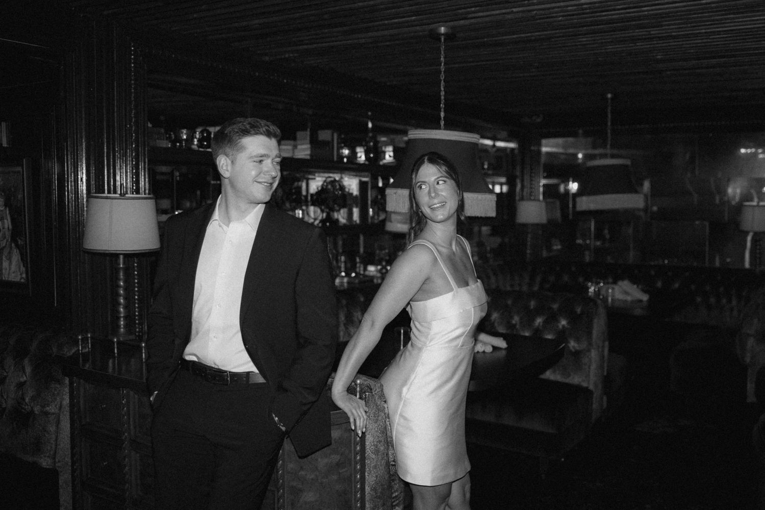A vintage black and white photograph showing a couple in formal attire at what appears to be a social gathering.