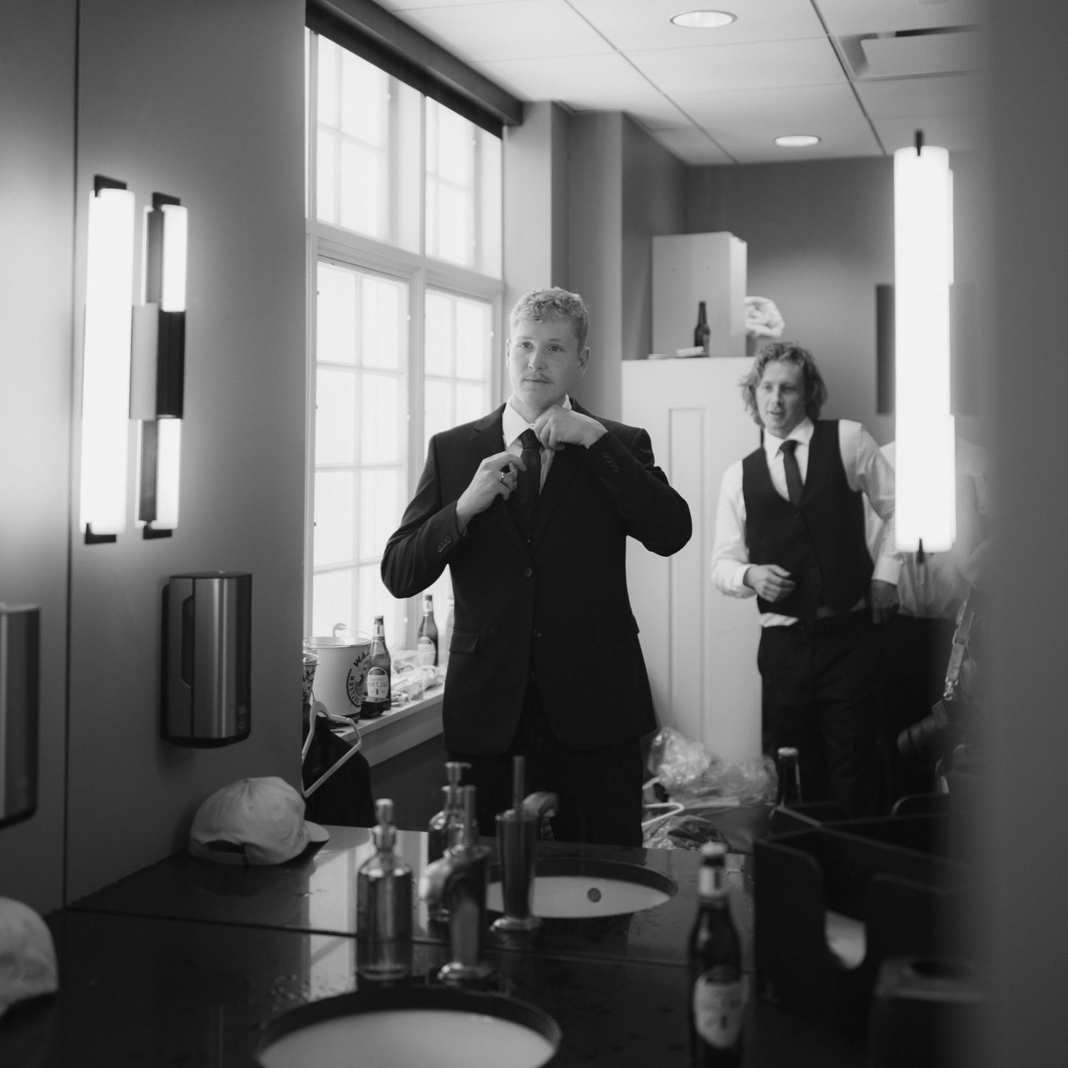Black and white office hallway scene with people in business attire standing and conversing in a modern workspace.