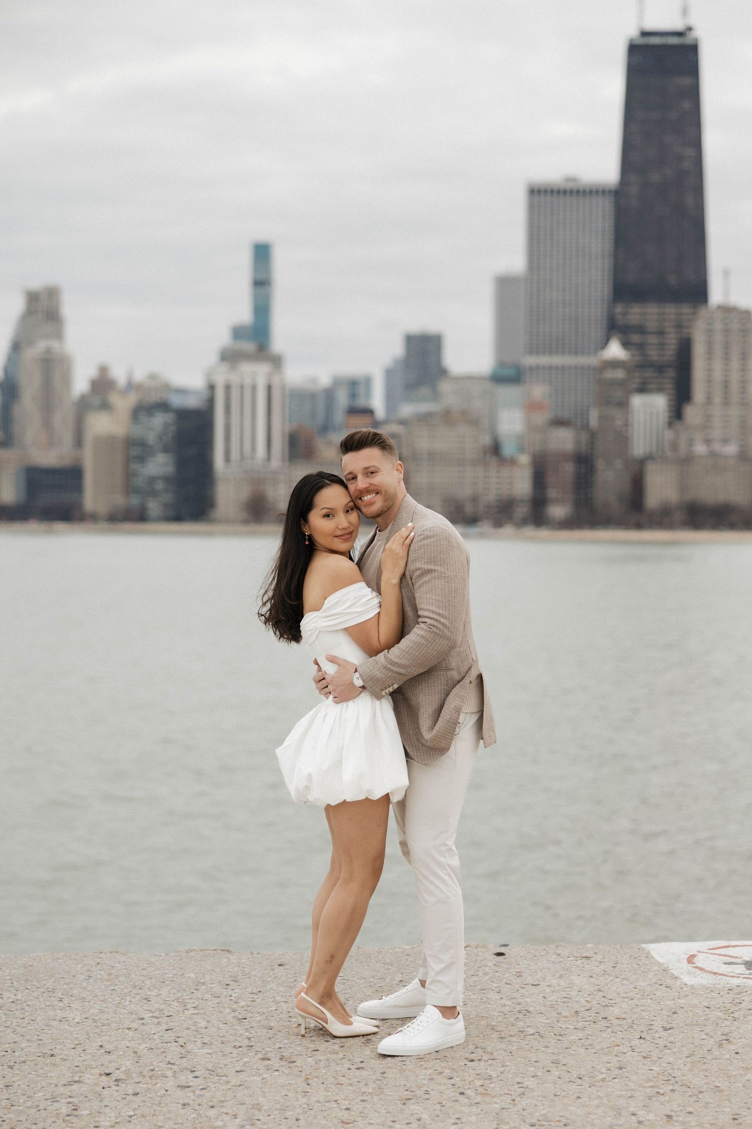 Smiling couple posing together with Chicago city skyline and lake in background.