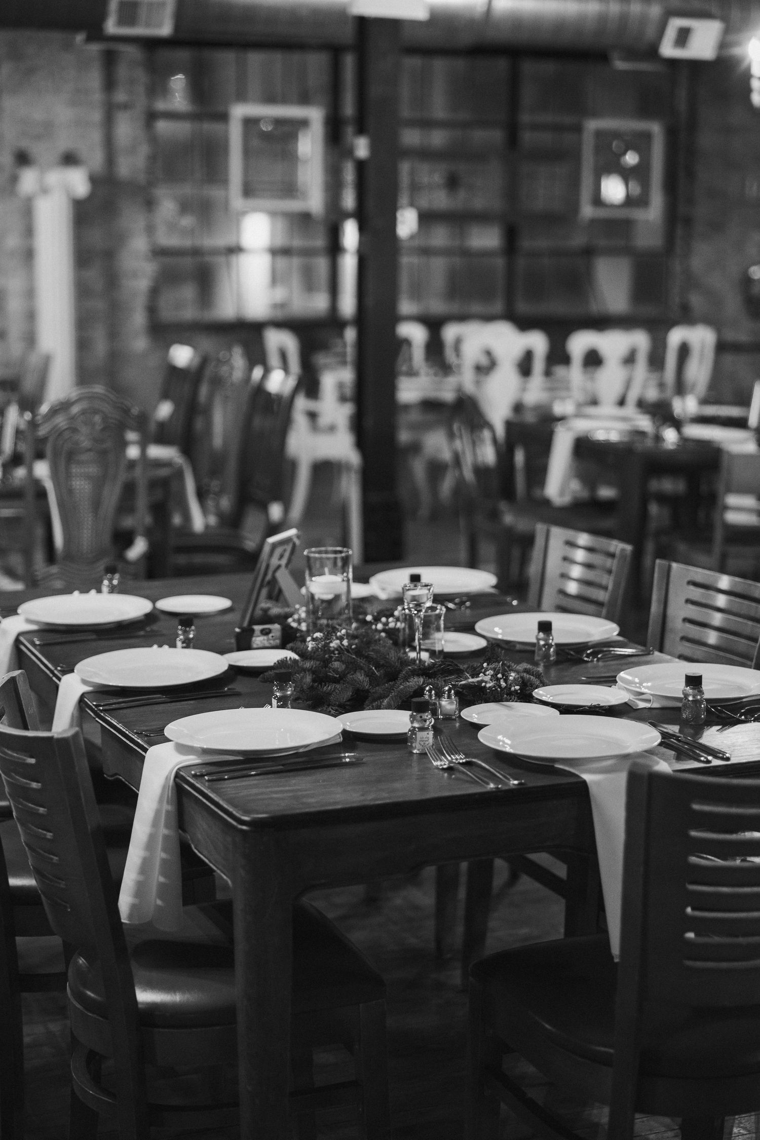 Empty restaurant interior with tables set for dinner service in black and white monochromatic style.