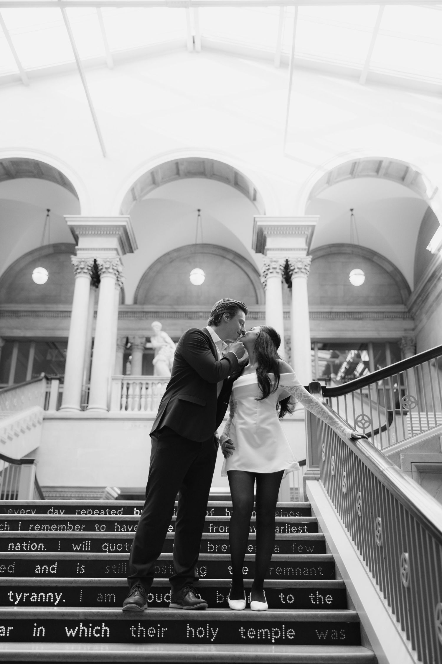 Black and white photo of a couple on grand marble stairs with text written on the steps.