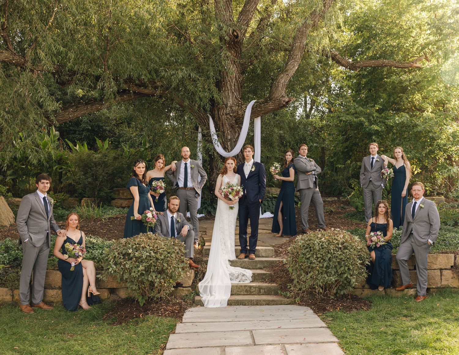 Wedding ceremony in progress at an outdoor garden venue with guests seated on both sides.