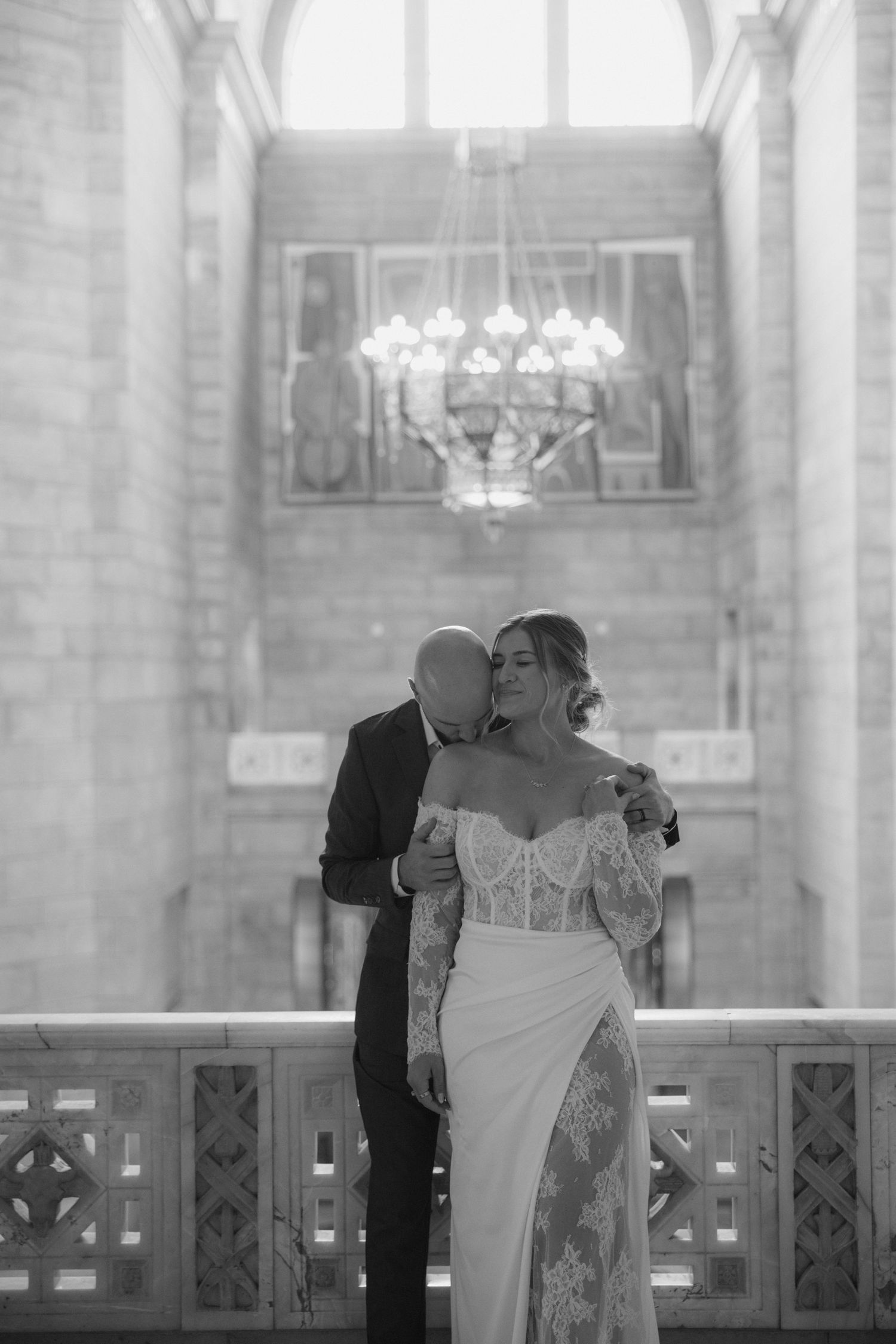 Couple sharing an intimate moment in a bright, airy church interior with arched windows.
