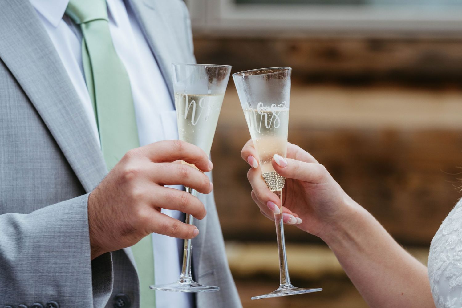 Bride and groom toasting with elegant champagne flutes at outdoor wedding celebration.