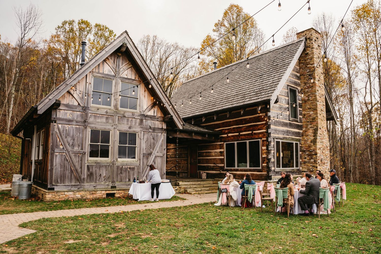 Rustic log cabin wedding venue with guests gathered outside during an autumn outdoor ceremony.