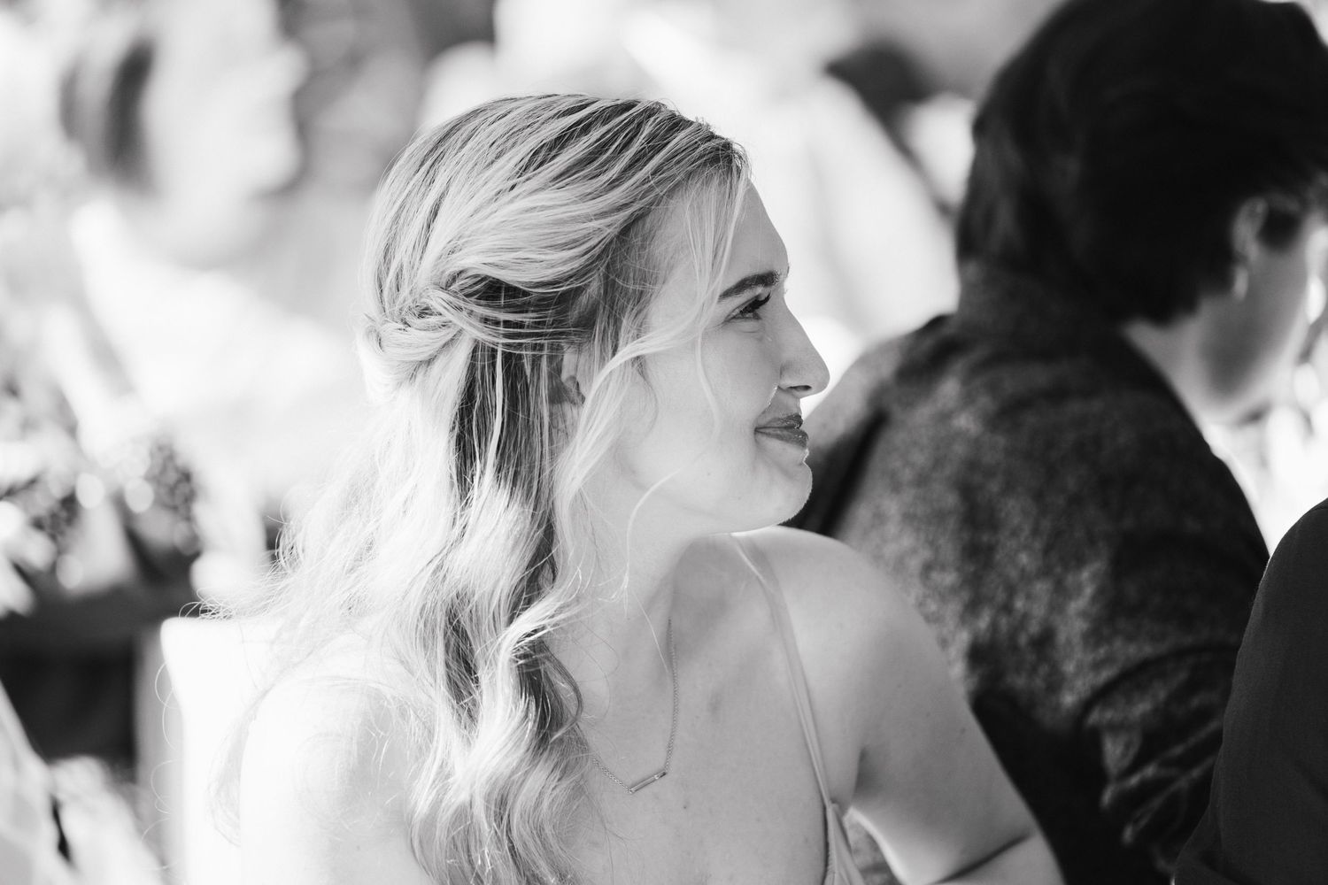 Black and white portrait of smiling blonde wedding guest with wavy hair.