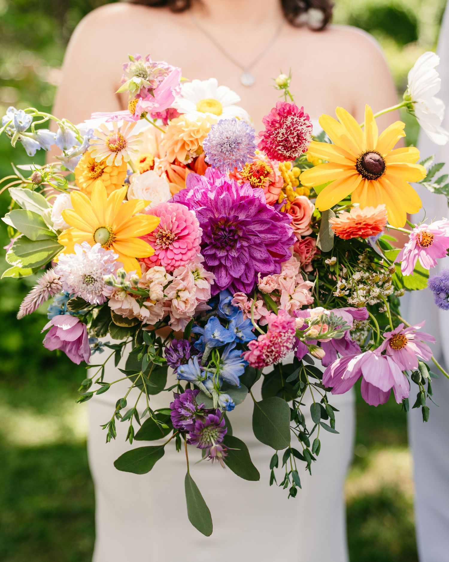 Vibrant bridal bouquet featuring yellow dahlias, pink cosmos, and mixed wildflowers in full bloom.