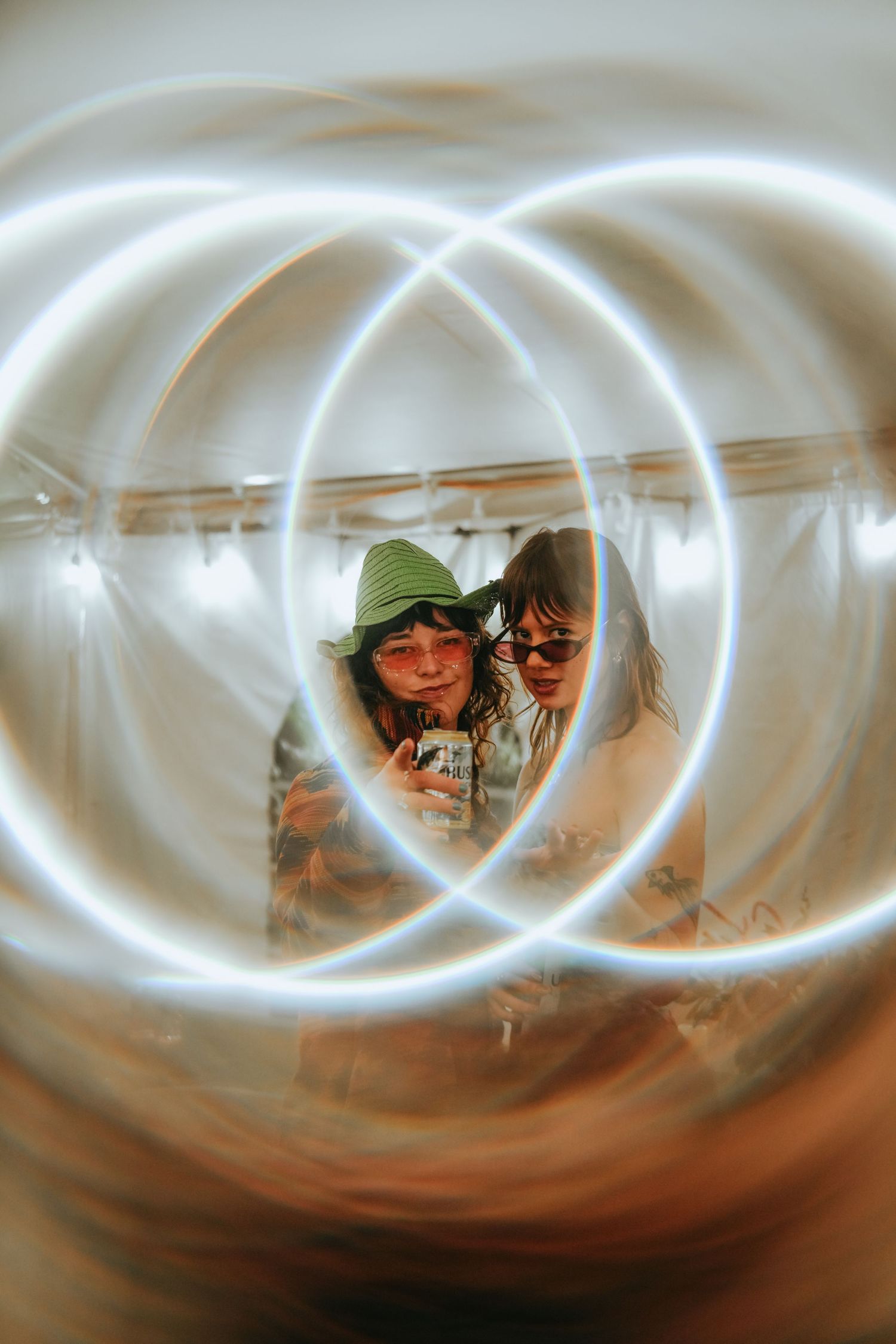 Two people look at a phone surrounded by swirling light painting circles in a creative photo.