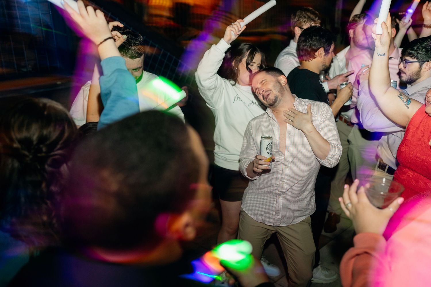 Crowd of guests dancing and celebrating at a lively wedding reception party.