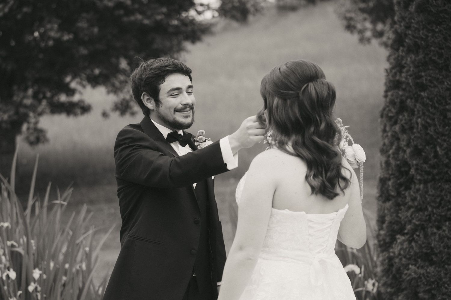 Black and white photo of groom tenderly touching brides face during first look.