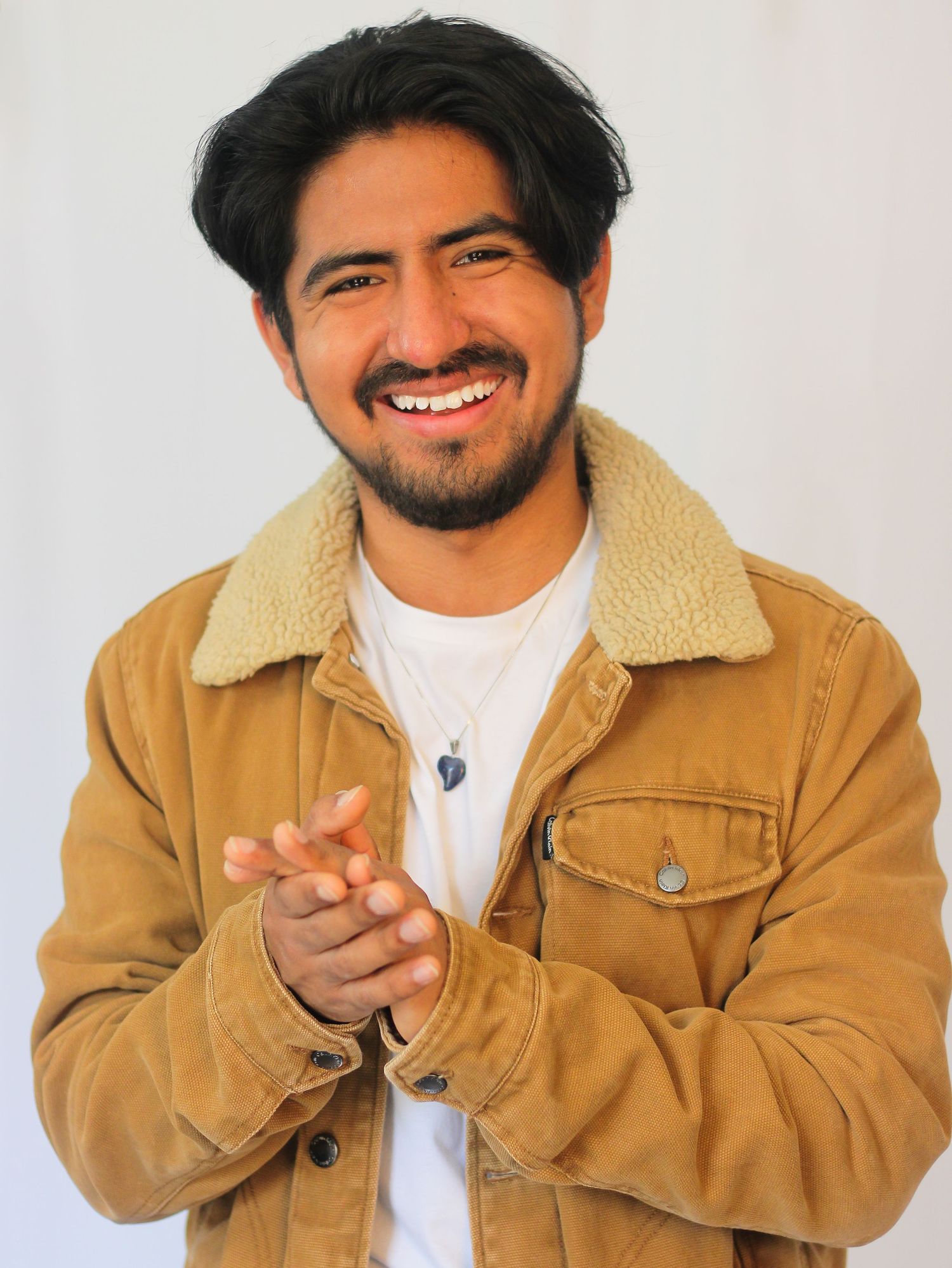 Portrait series in tan jacket showing expressive poses against white backdrop.
