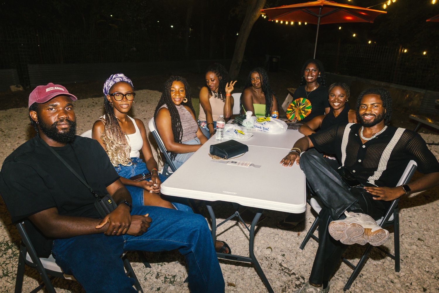 Group of friends gathered around a white table outdoors at night for a casual dinner.