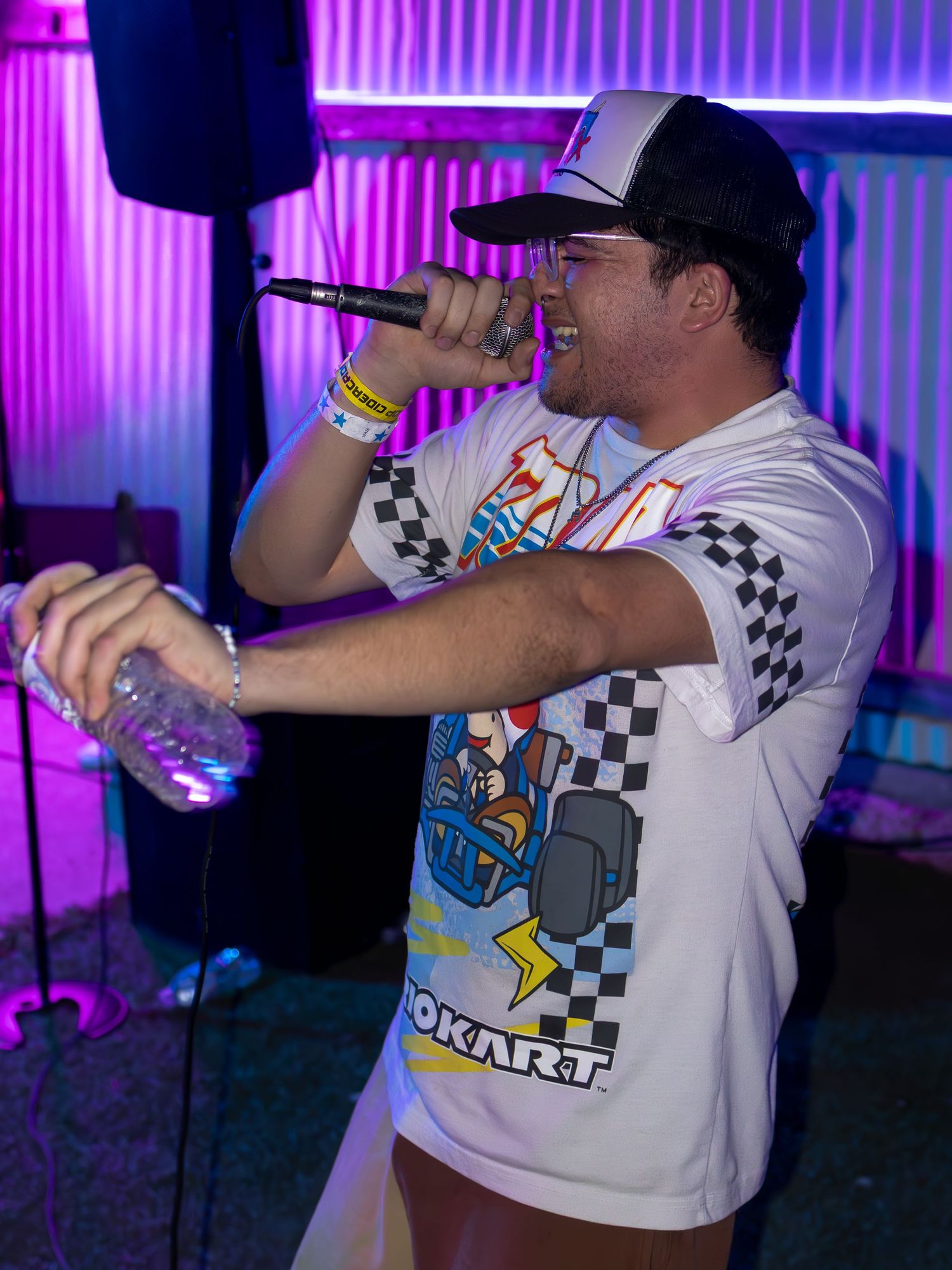 Energetic stage performance with performer in gaming t-shirt under purple venue lighting.