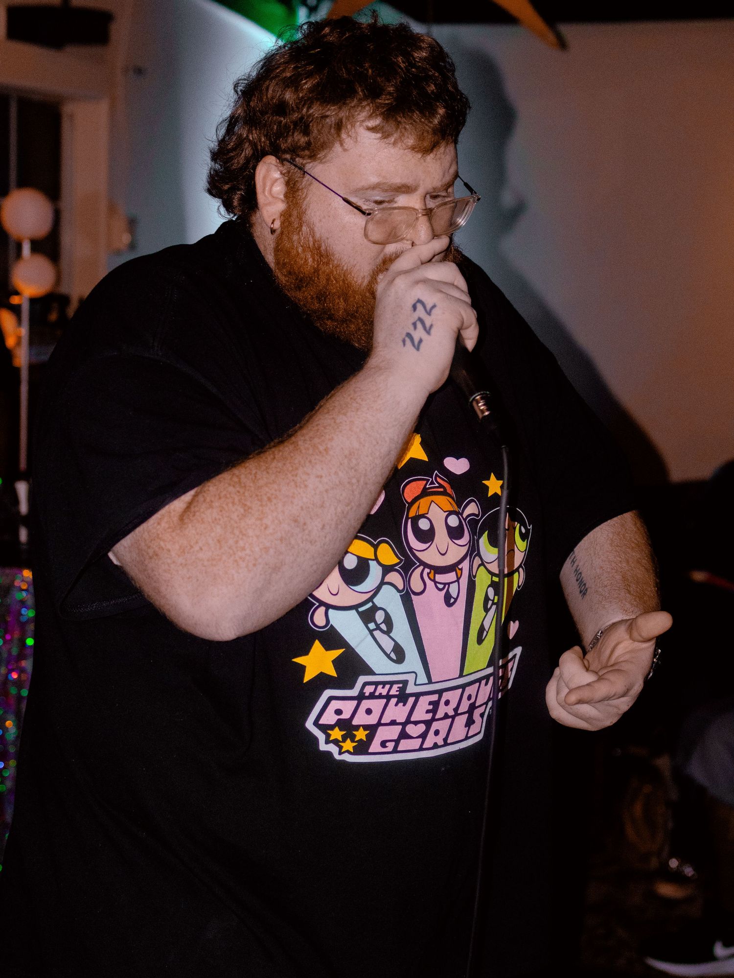 Energetic performance shot with colorful stage lighting and cartoon character t-shirt design.