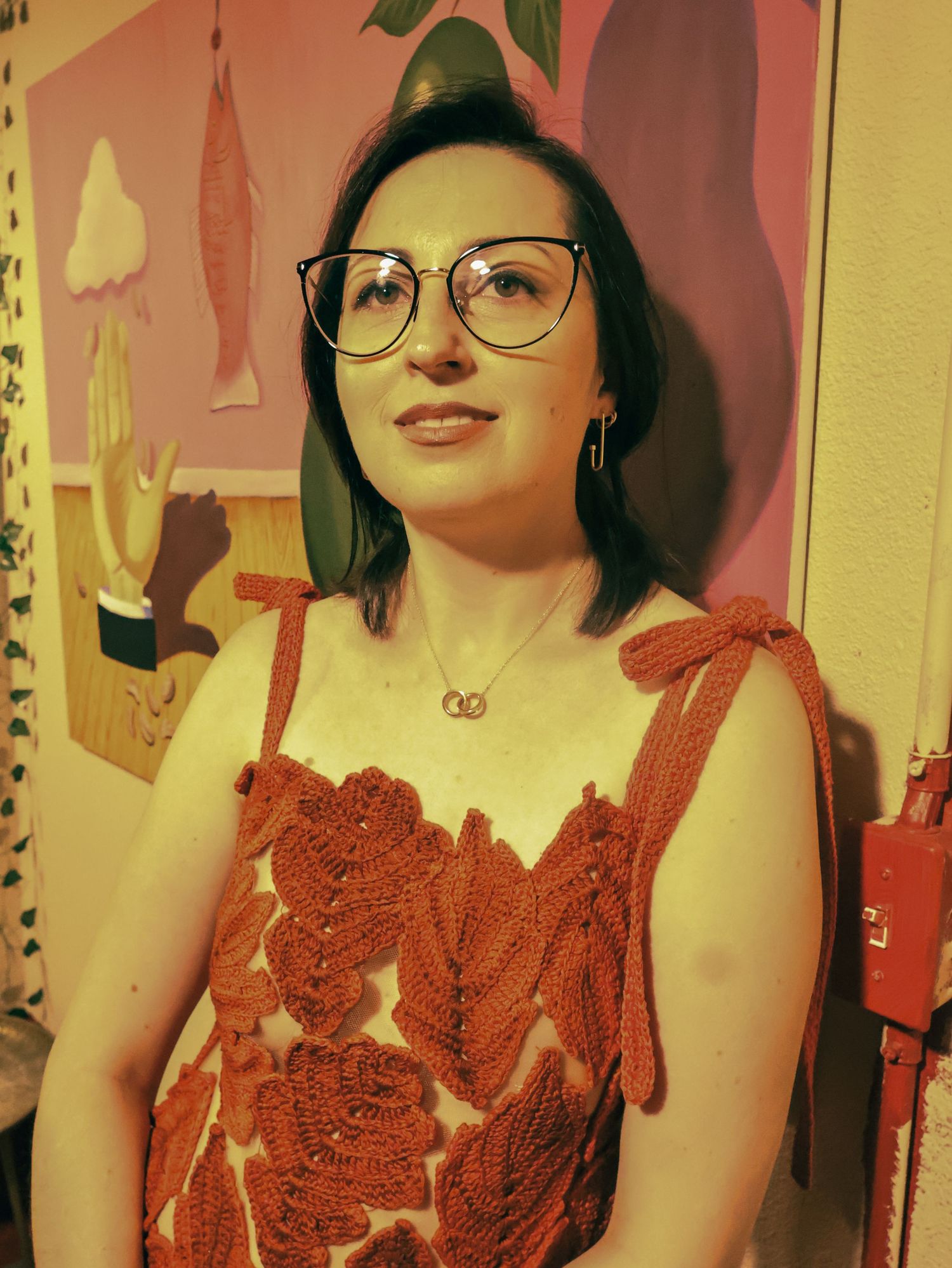 A vintage-style red dress with detailed lacework is photographed in a warm-toned setting.