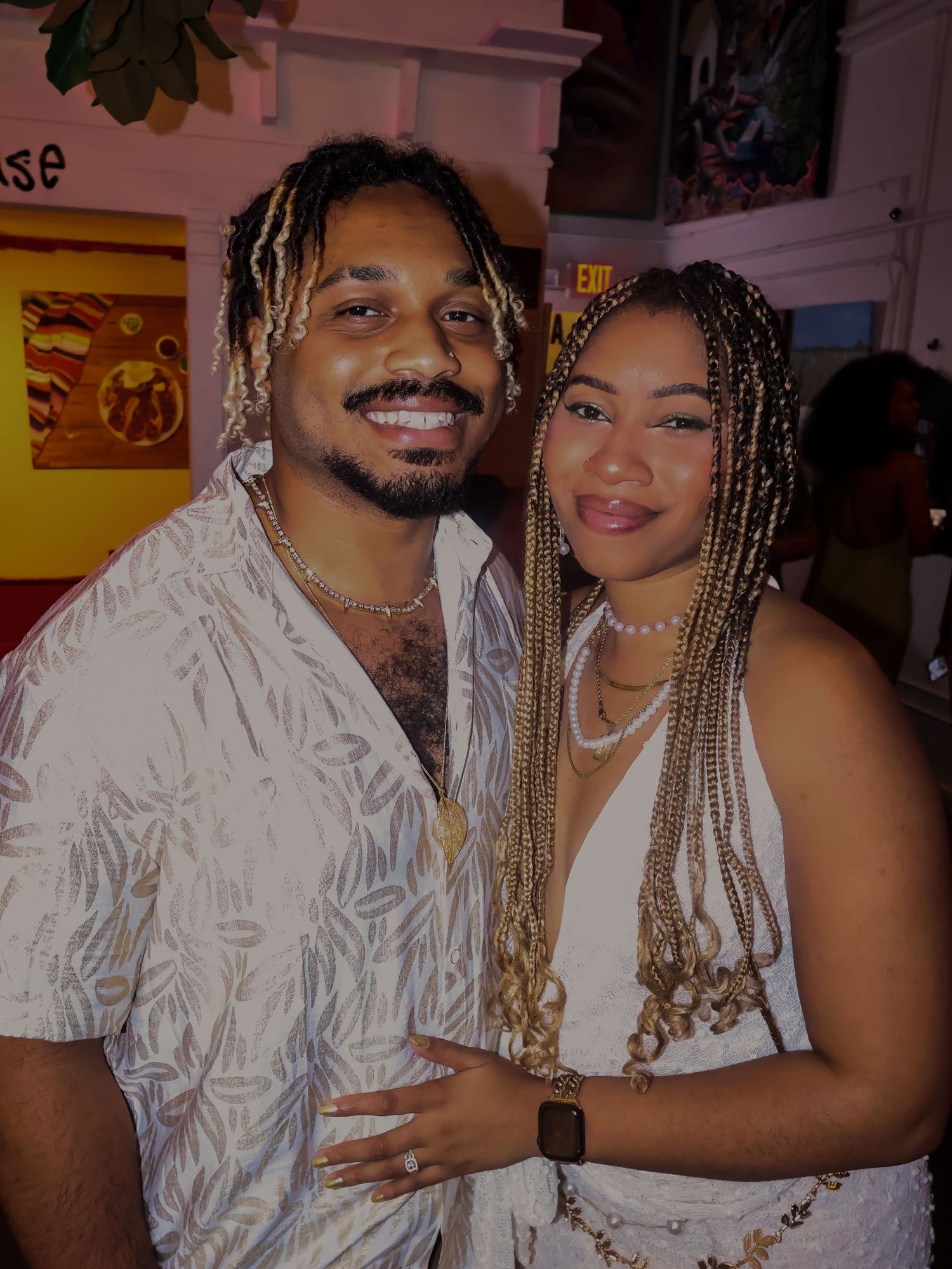 Couple in coordinated outfits posing together at a social gathering.